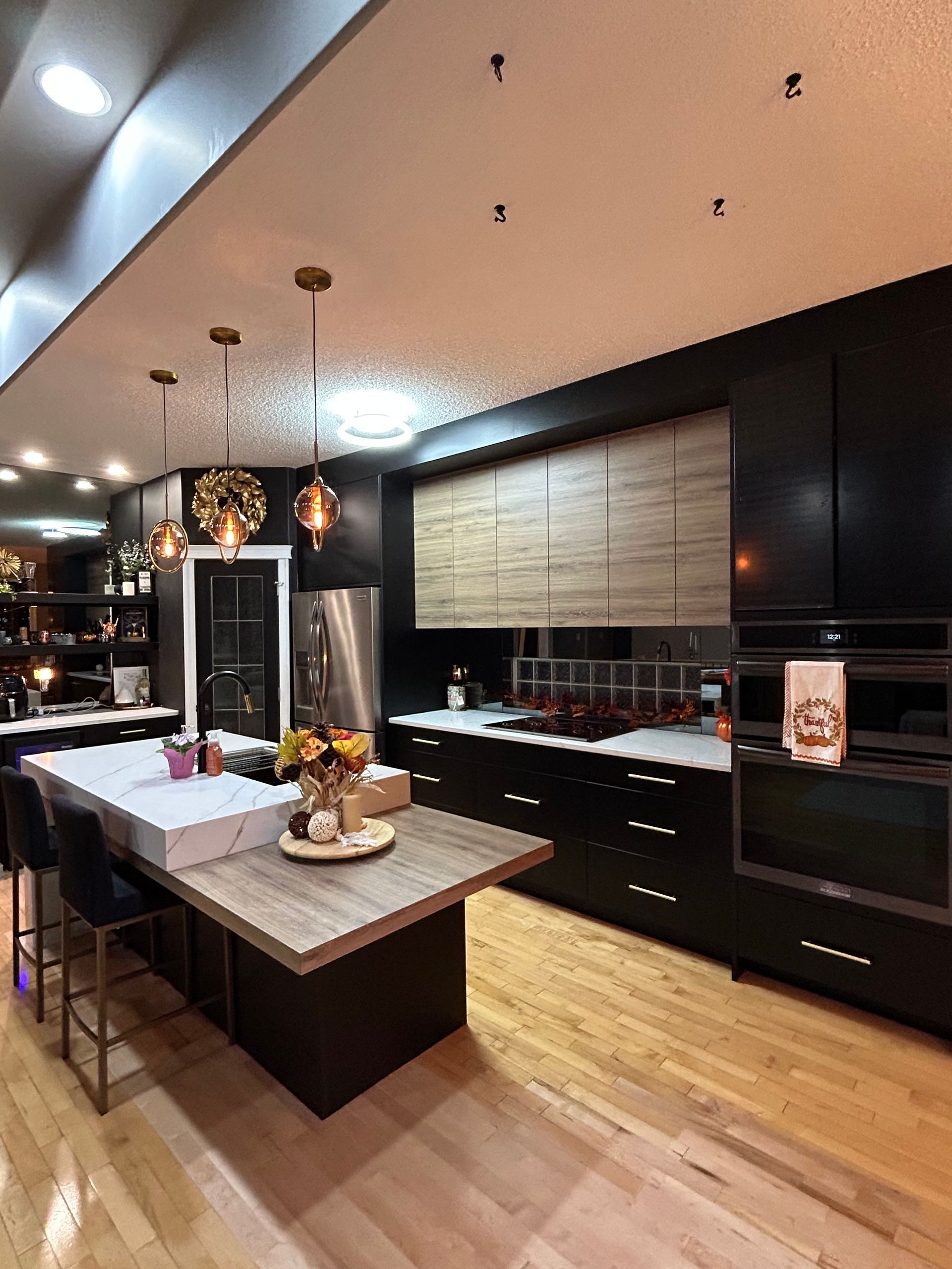 A kitchen with black cabinets and wooden floors