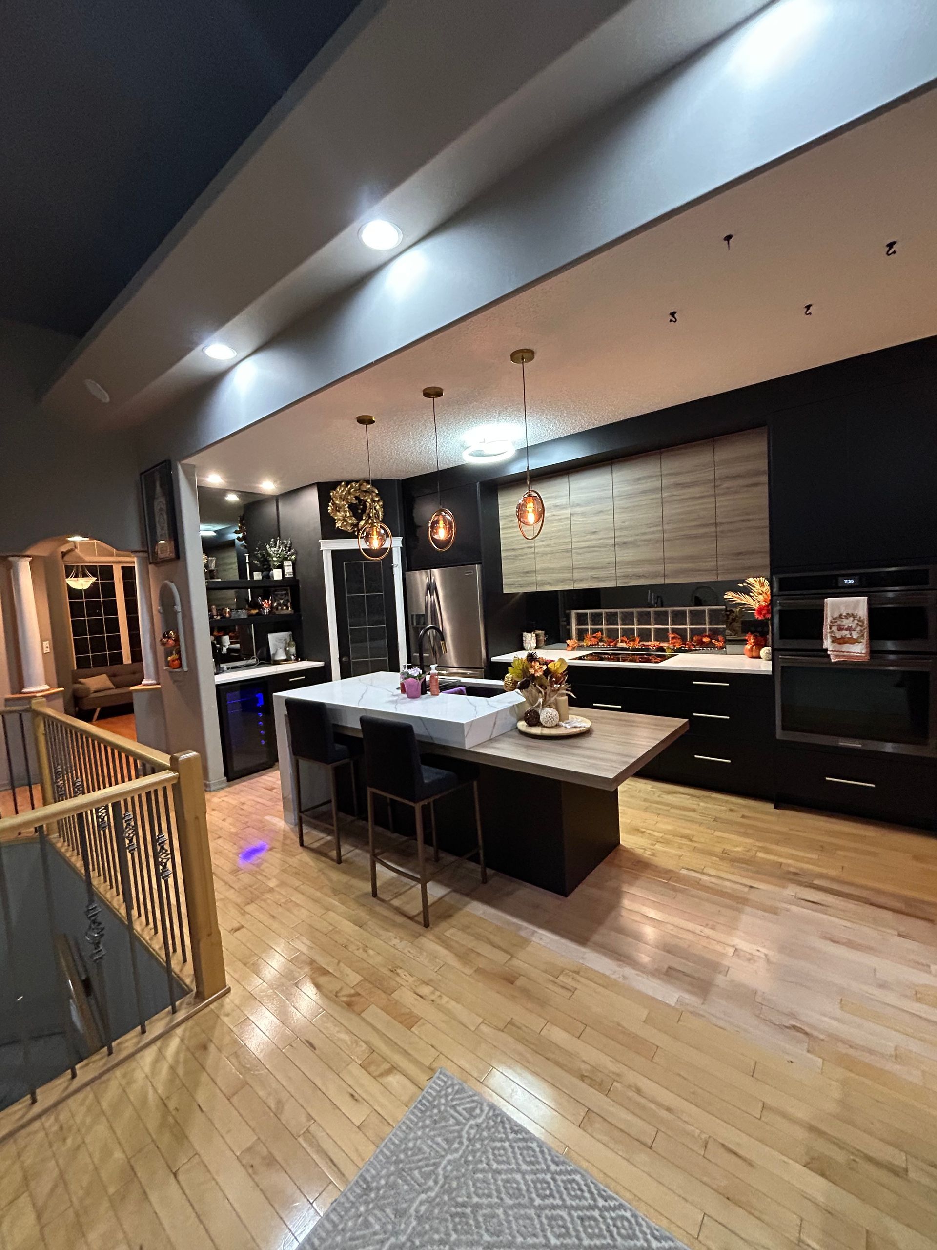 A kitchen with black cabinets and a large island in the middle.