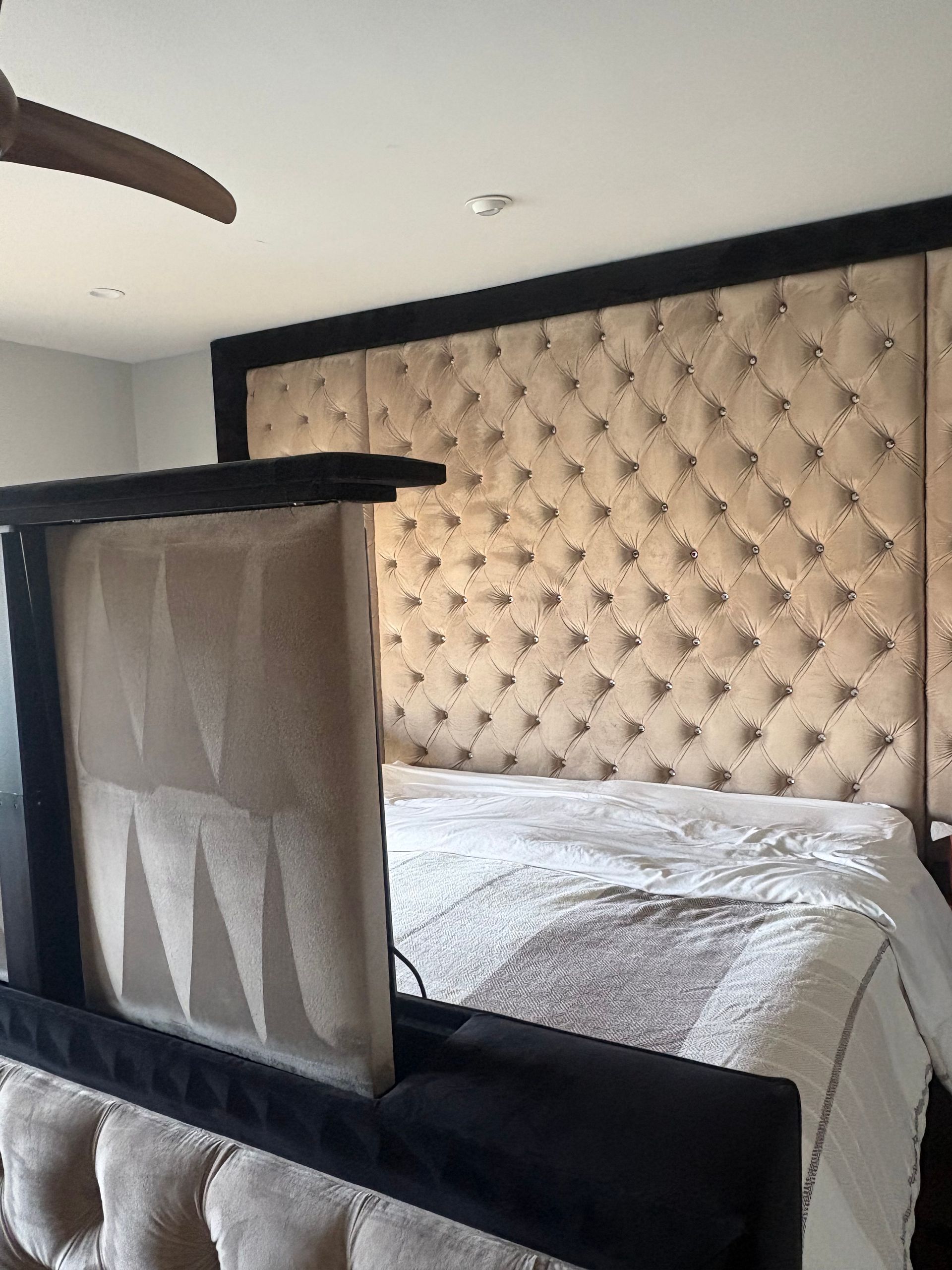 A bed with a large, tufted headboard, and a TV that rises from the foot.