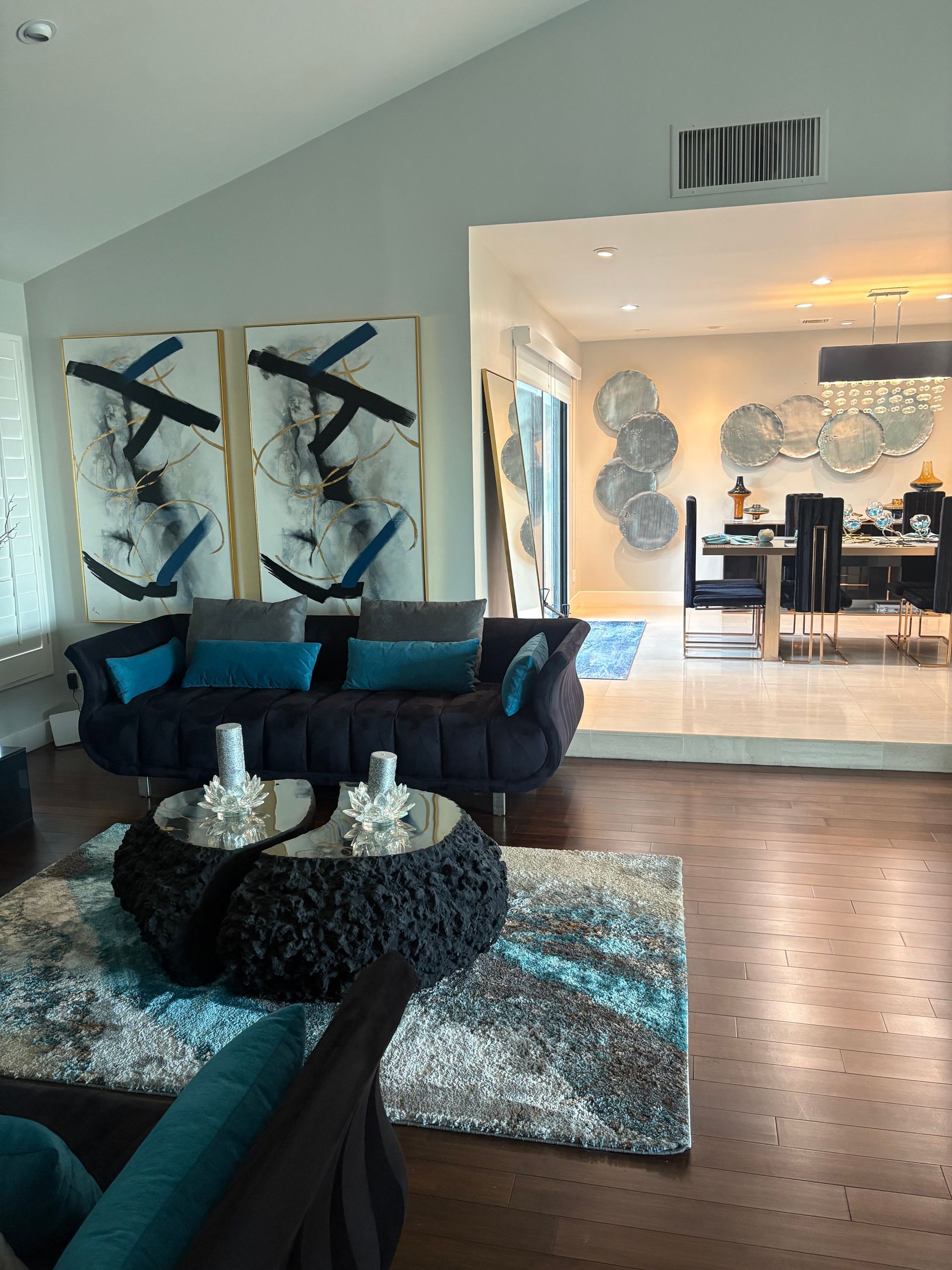 Living room with dark blue sofa, abstract art, and view into a dining area.