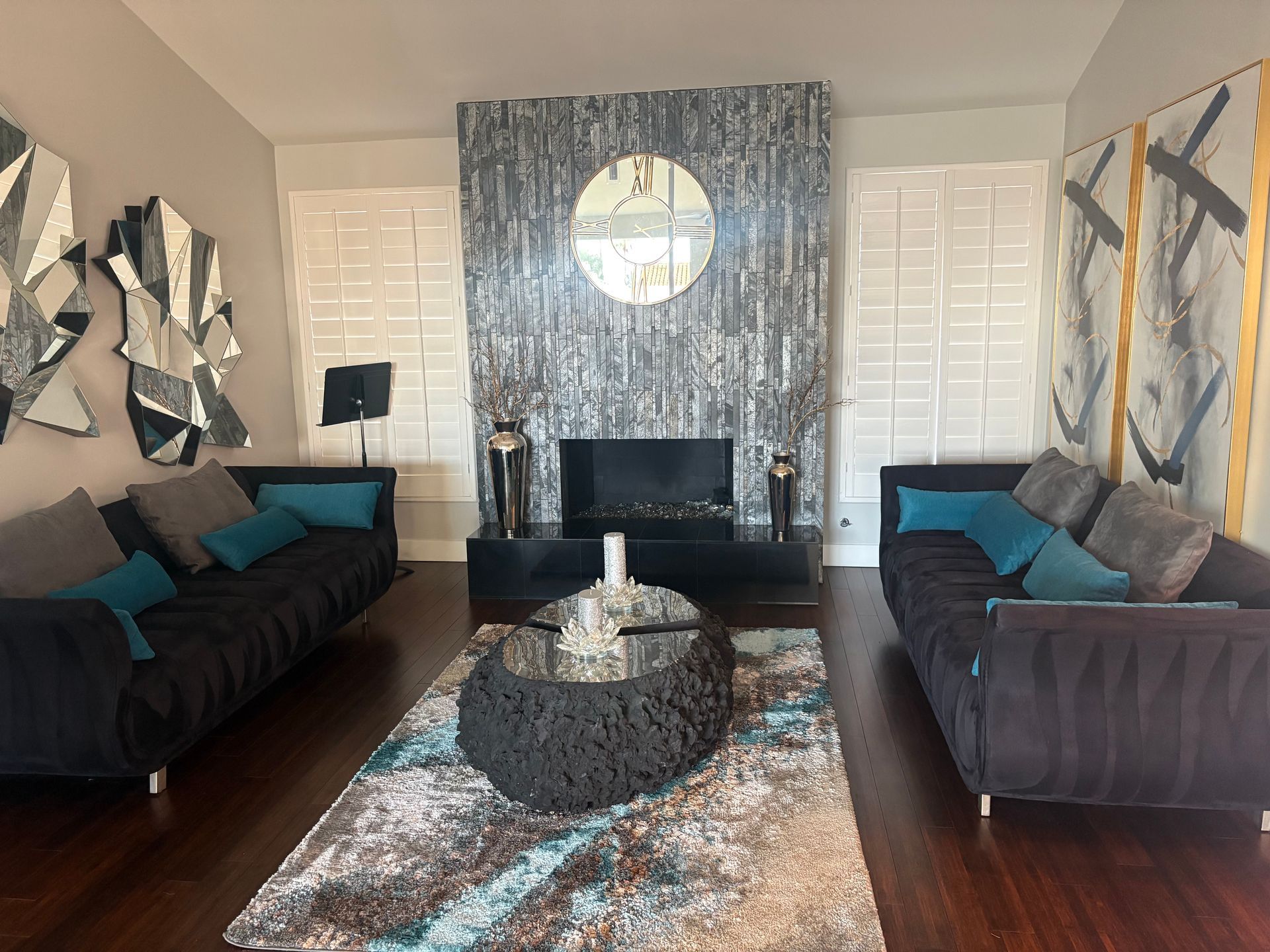 Living room with black sofas, fireplace, and abstract art.