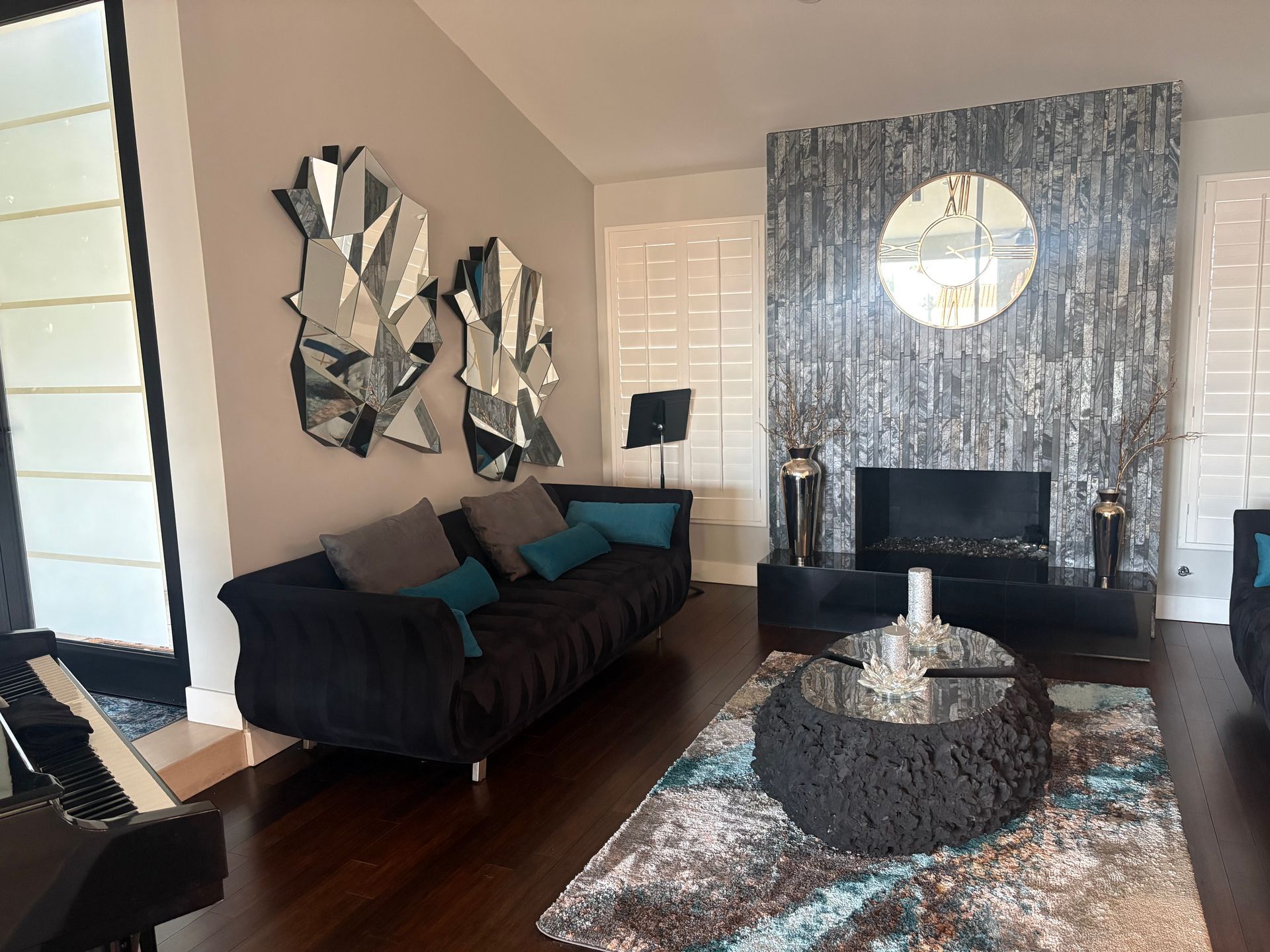 Living room with black sofa, modern art, fireplace, and patterned rug.