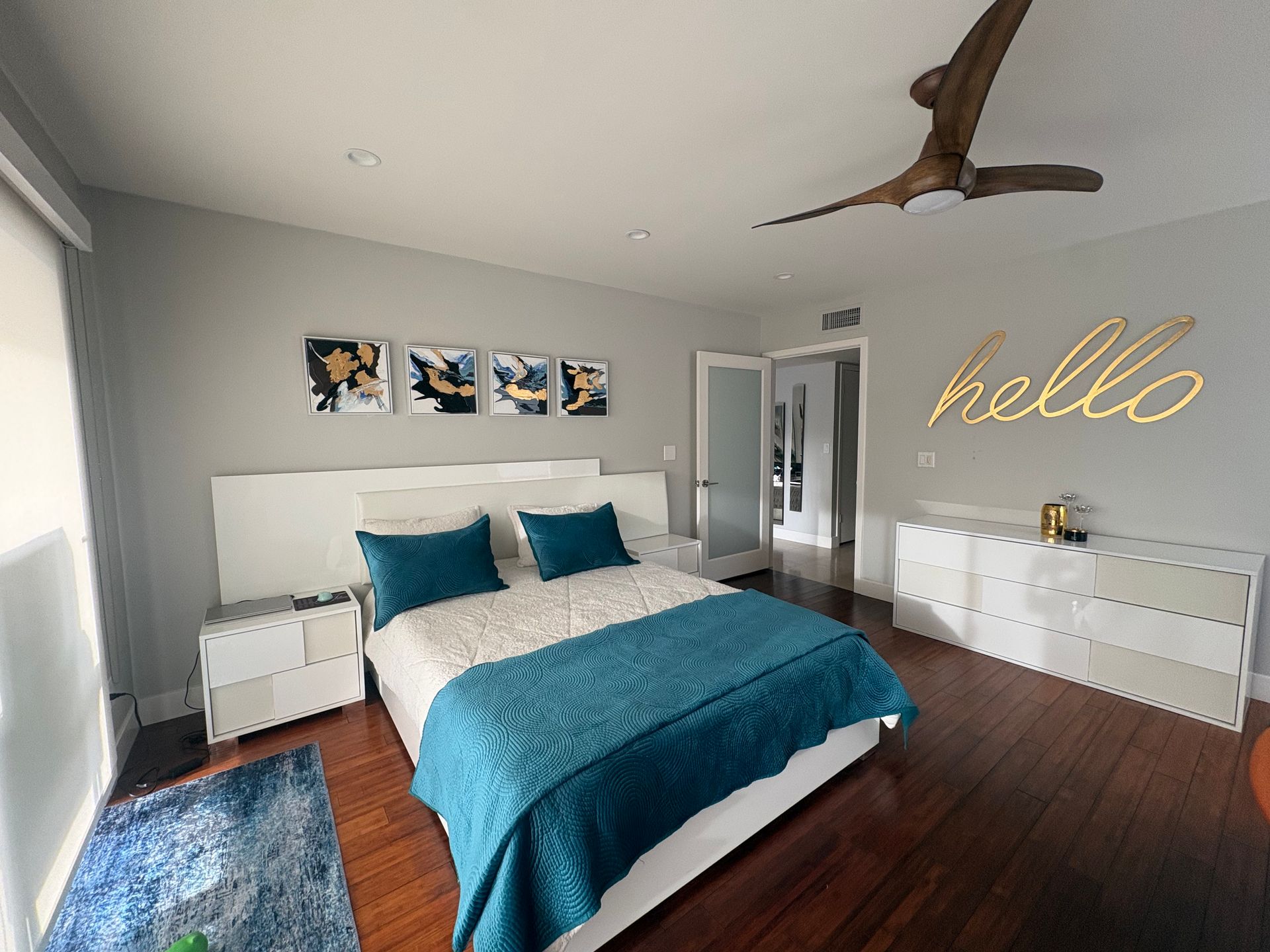 Bedroom with white bed, blue accents, wall art, and a gold