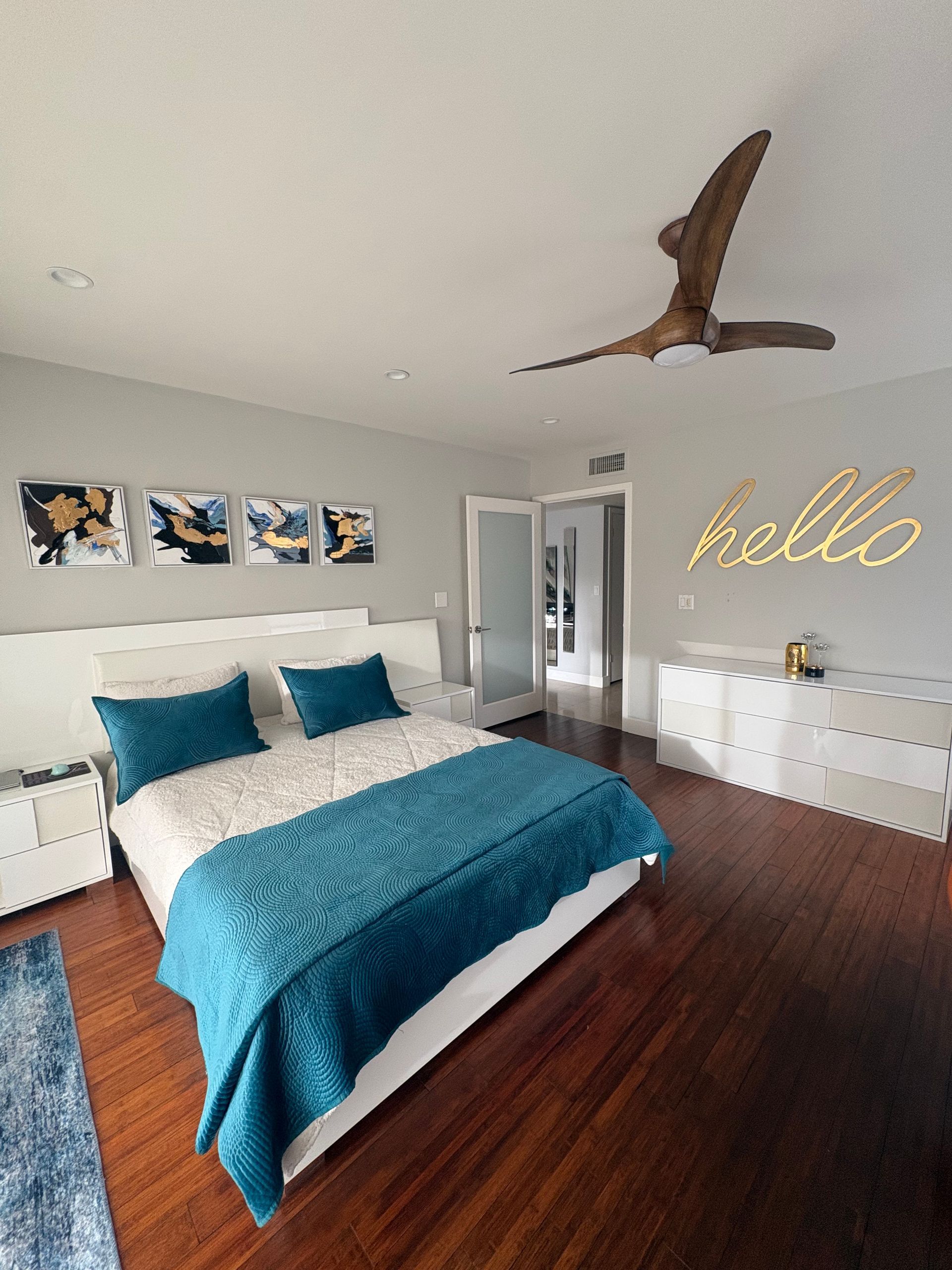 Bedroom with teal bedding, art above bed,
