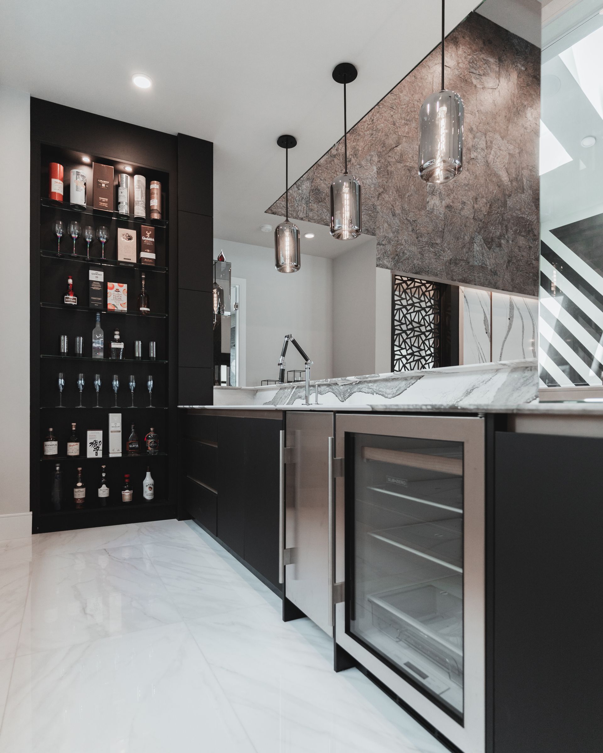 A kitchen with black cabinets and a stainless steel refrigerator