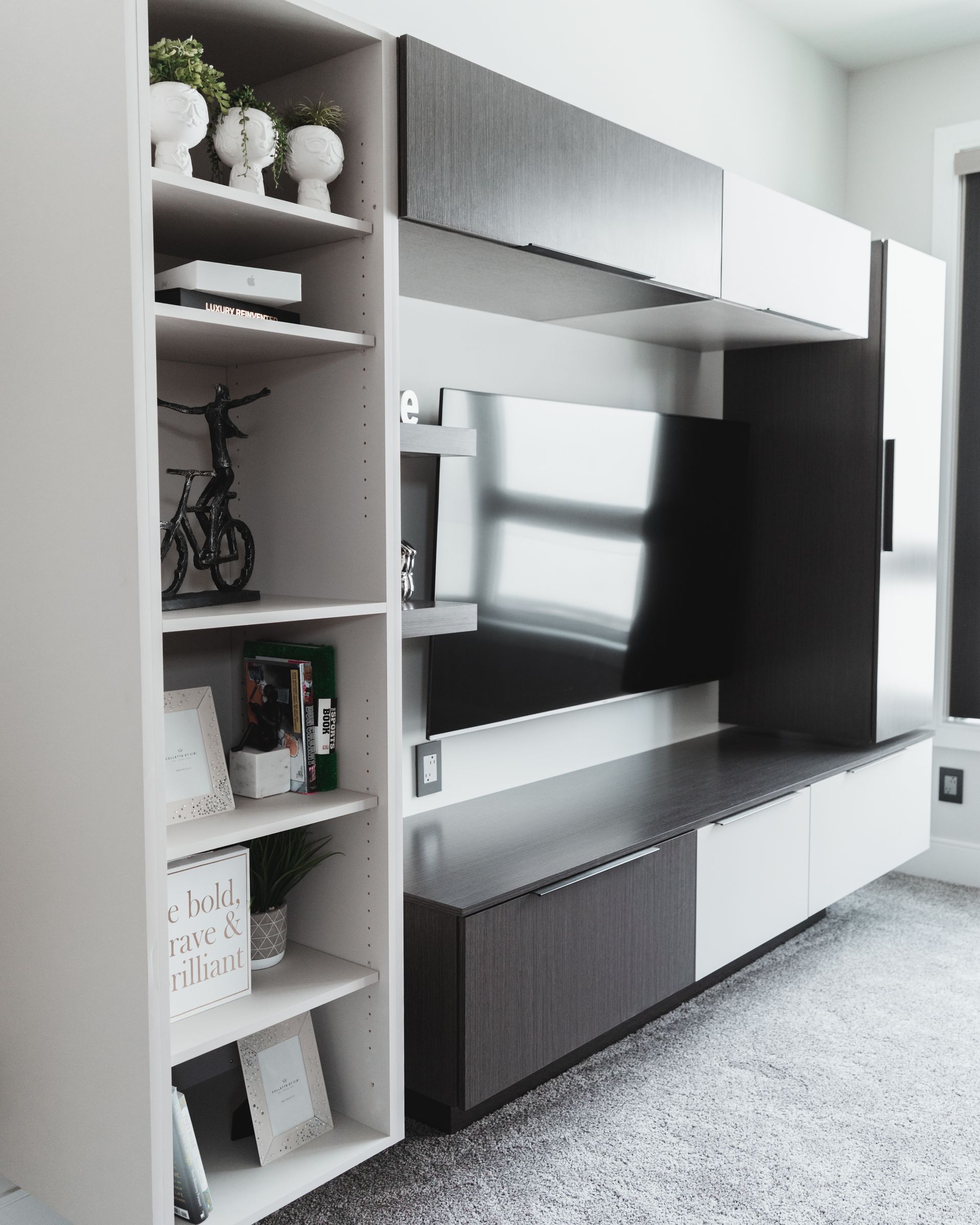 A living room with a flat screen tv and shelves.