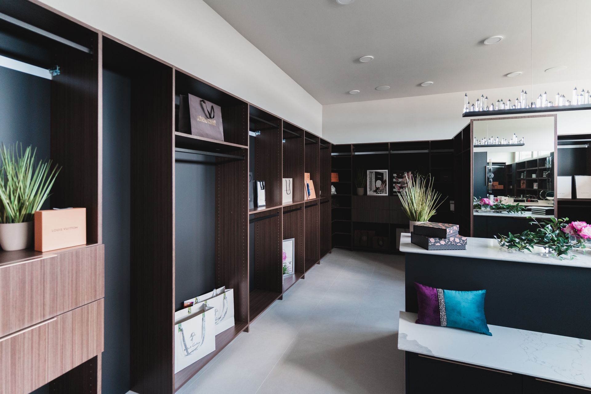 A walk in closet with lots of shelves and a bench