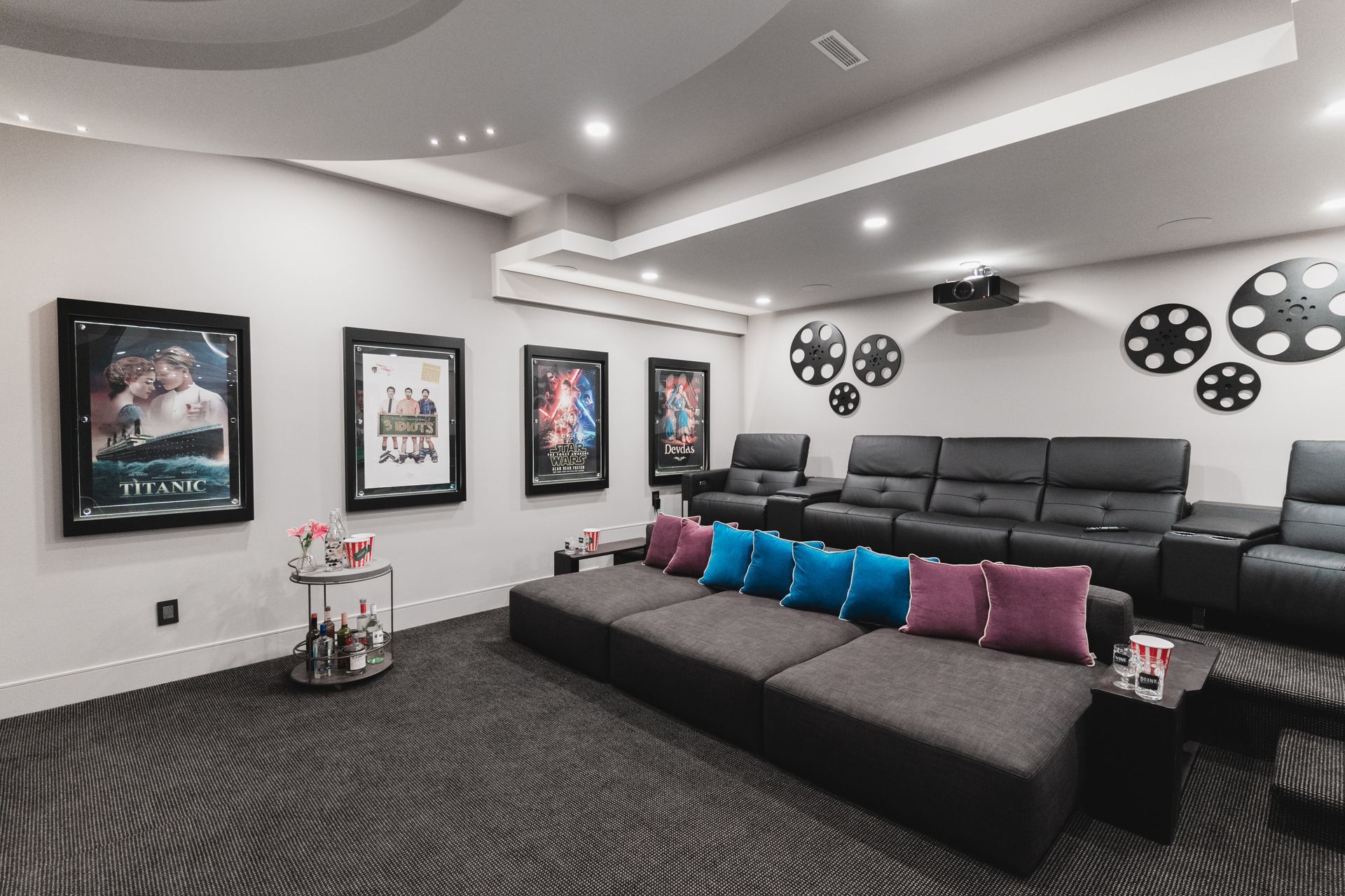 A home theater with a large couch , chairs , and a projector.