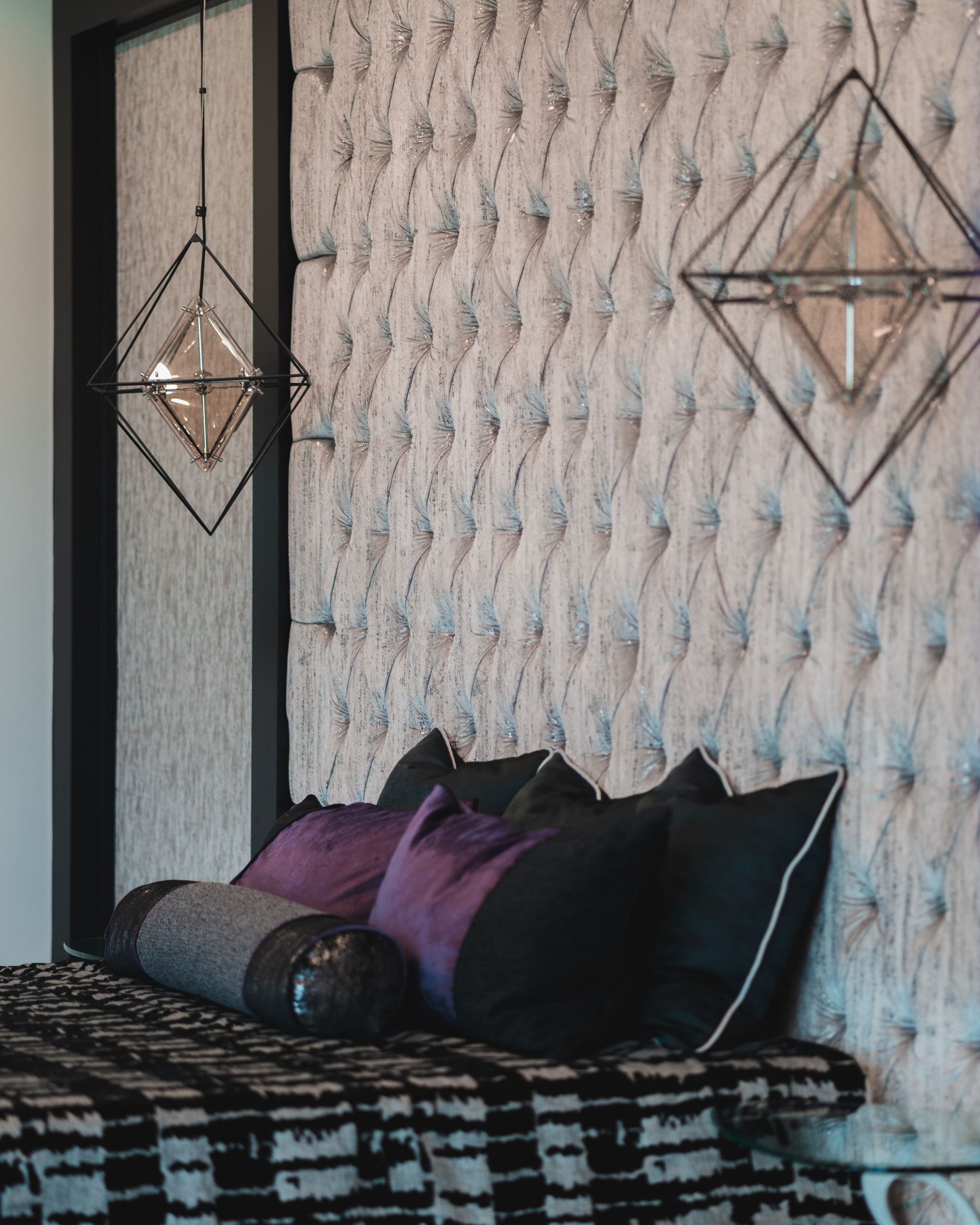 A bed with purple and black pillows on it in a bedroom