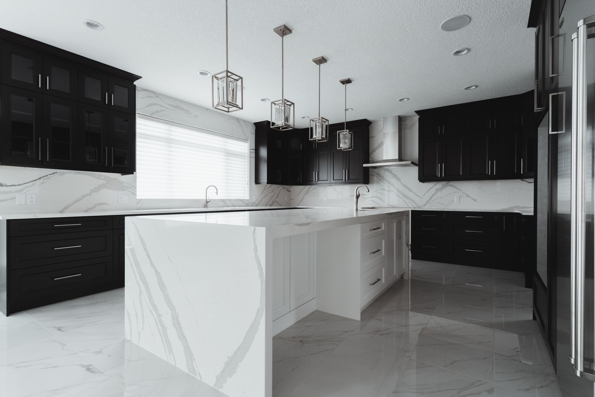 A kitchen with black cabinets and white counter tops and a large island.