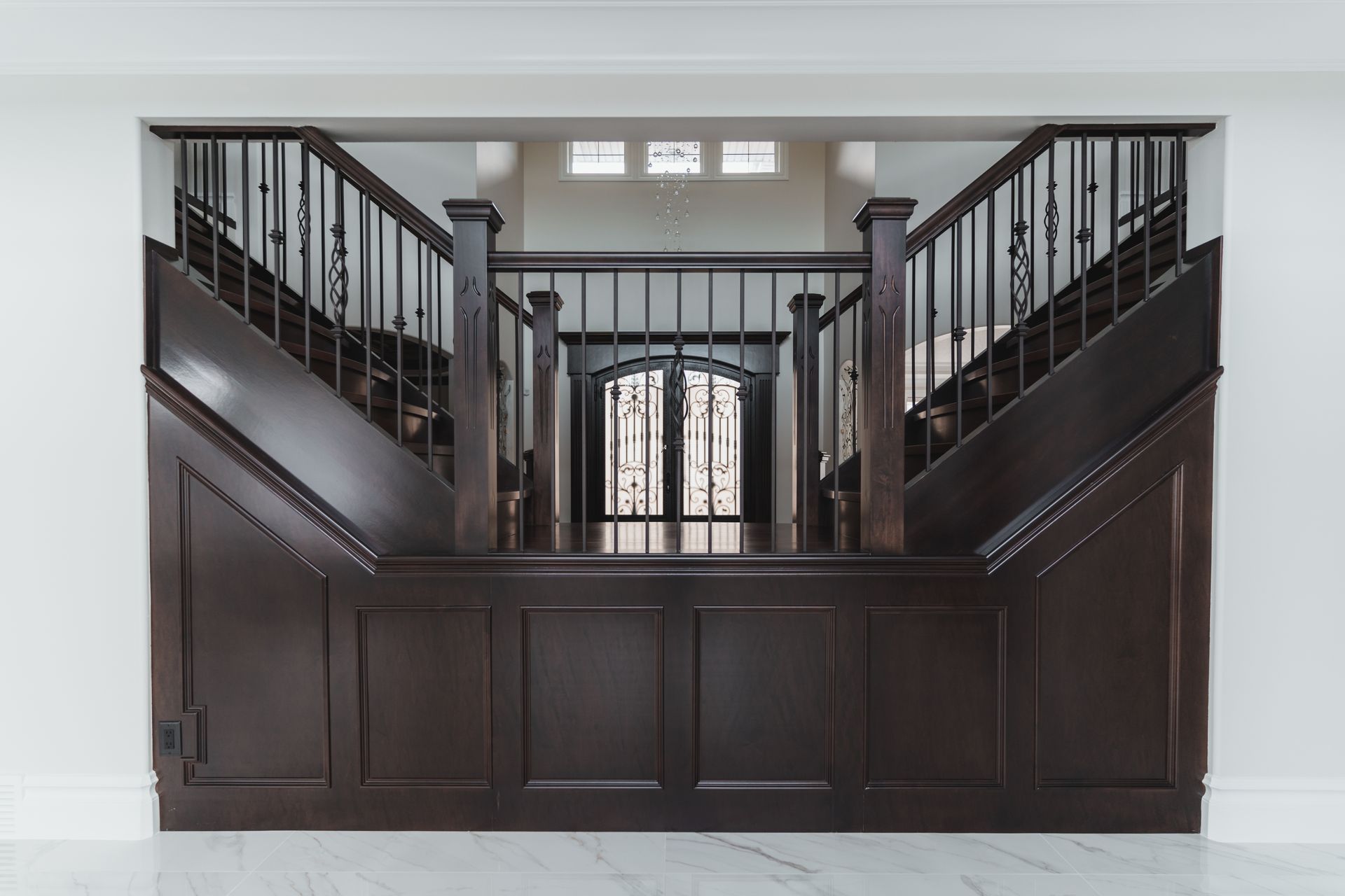 A wooden staircase with a wrought iron railing in a house.