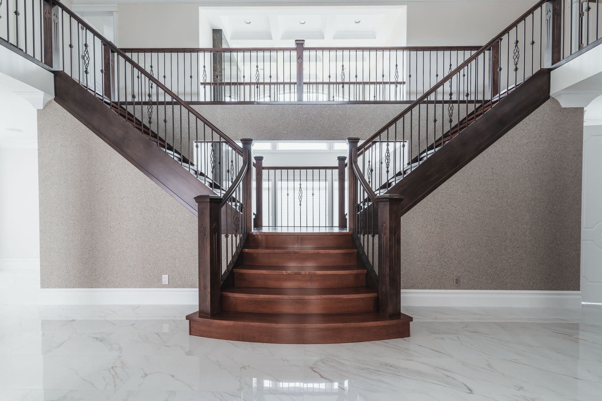 A large wooden staircase with a wrought iron railing in an empty room.