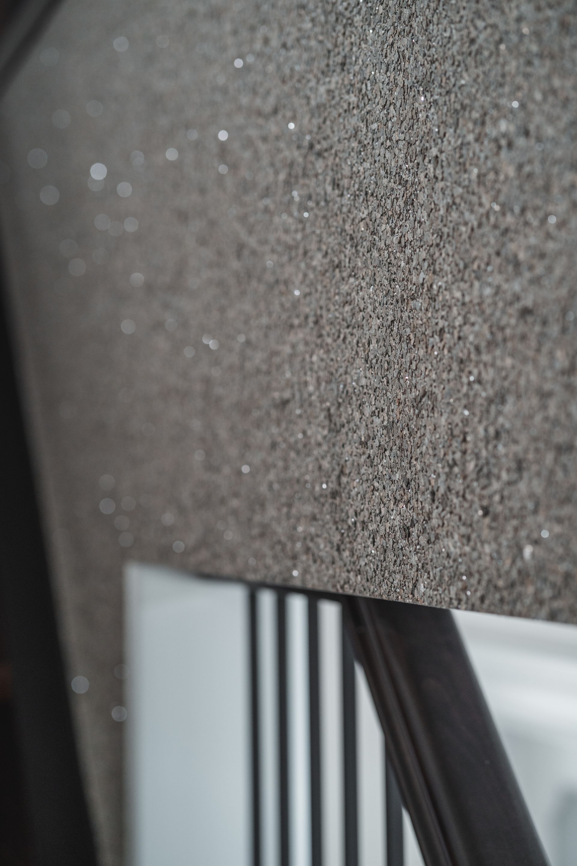 A close up of a staircase with a gray wall and a black railing.