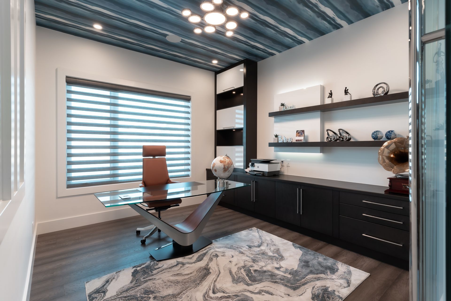 A home office with a desk , chair , shelves and a rug.