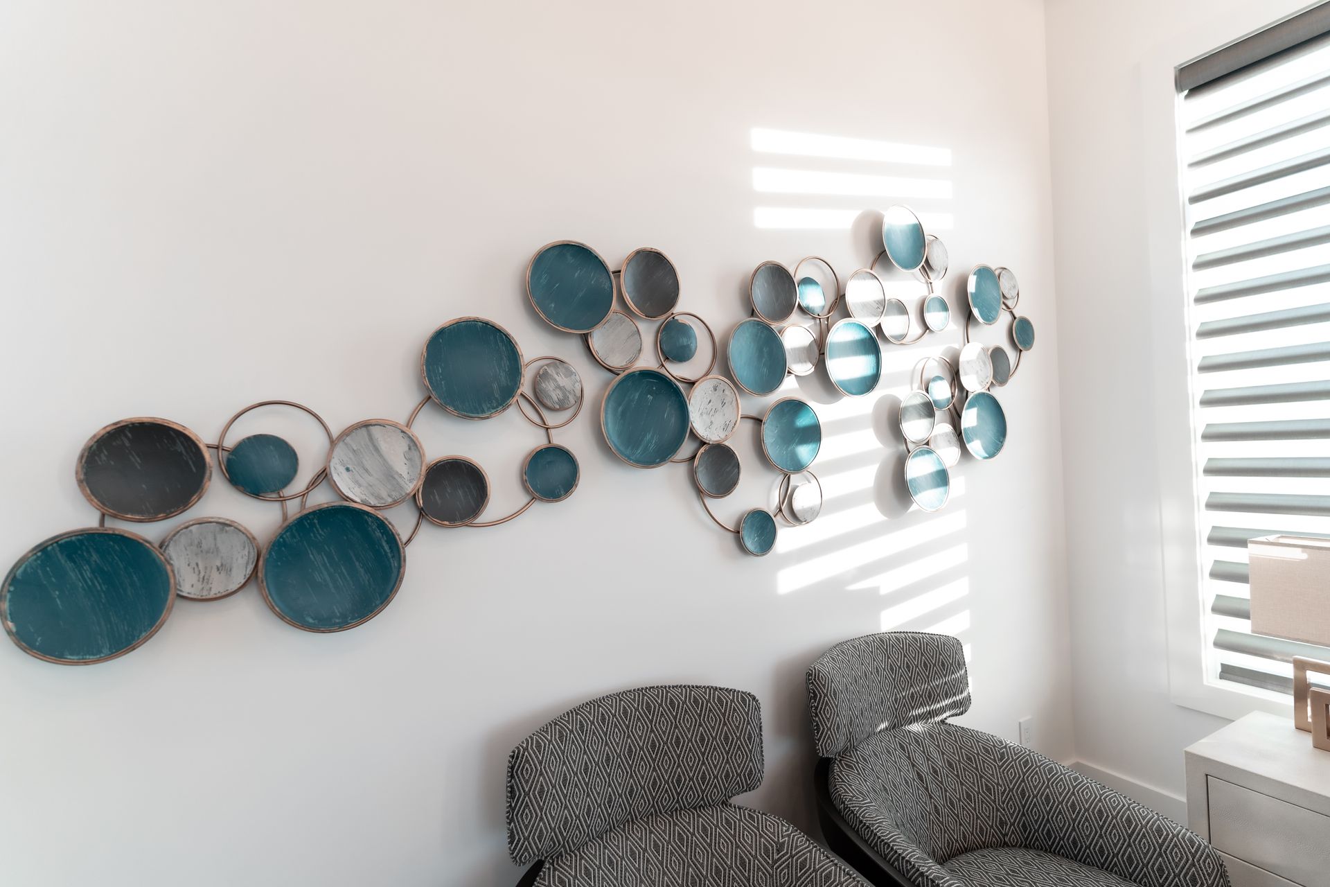 A living room with two chairs and a wall decoration.