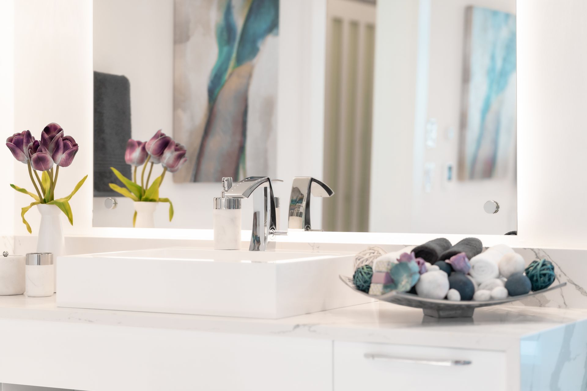 A bathroom with a sink , mirror , and vases of flowers.