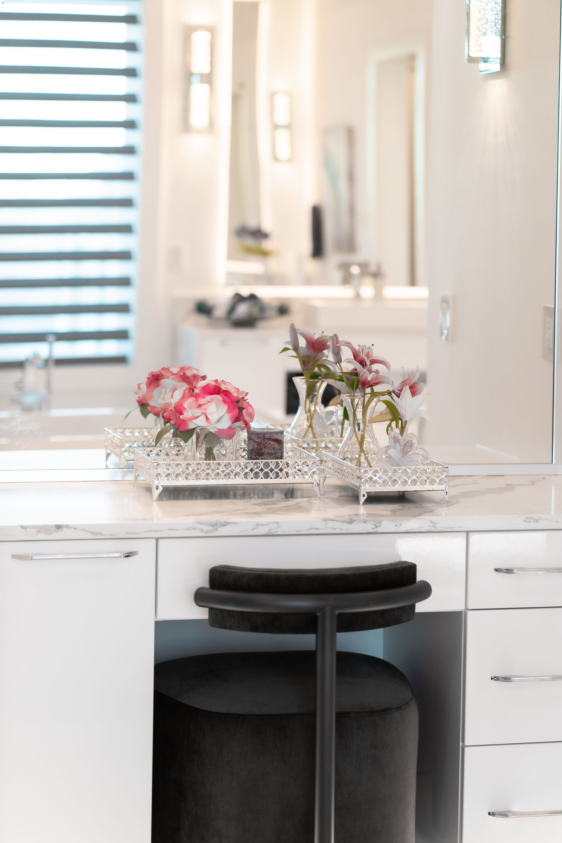 A vanity with a stool and flowers on it in a bathroom.