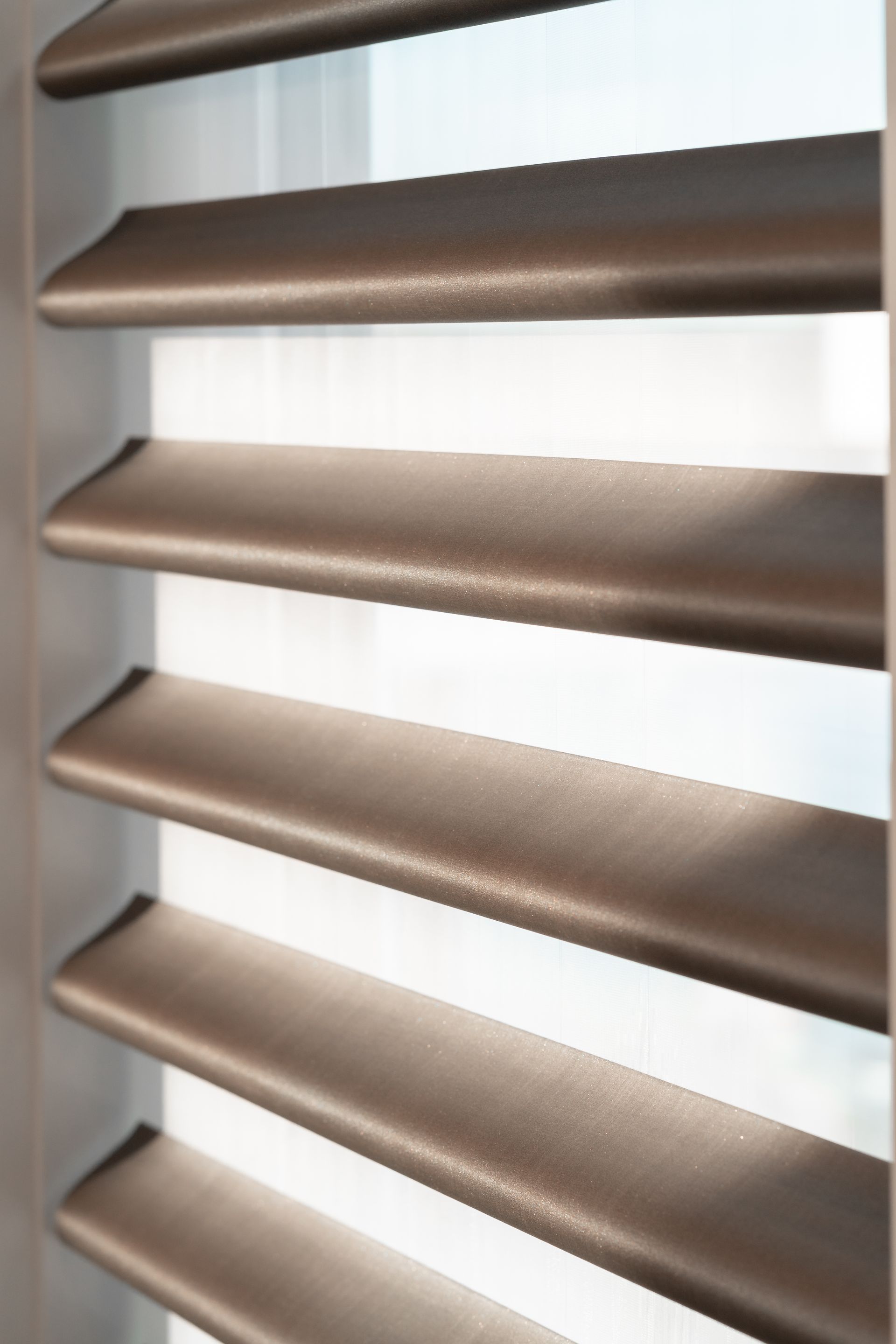A close up of a window with brown blinds on it