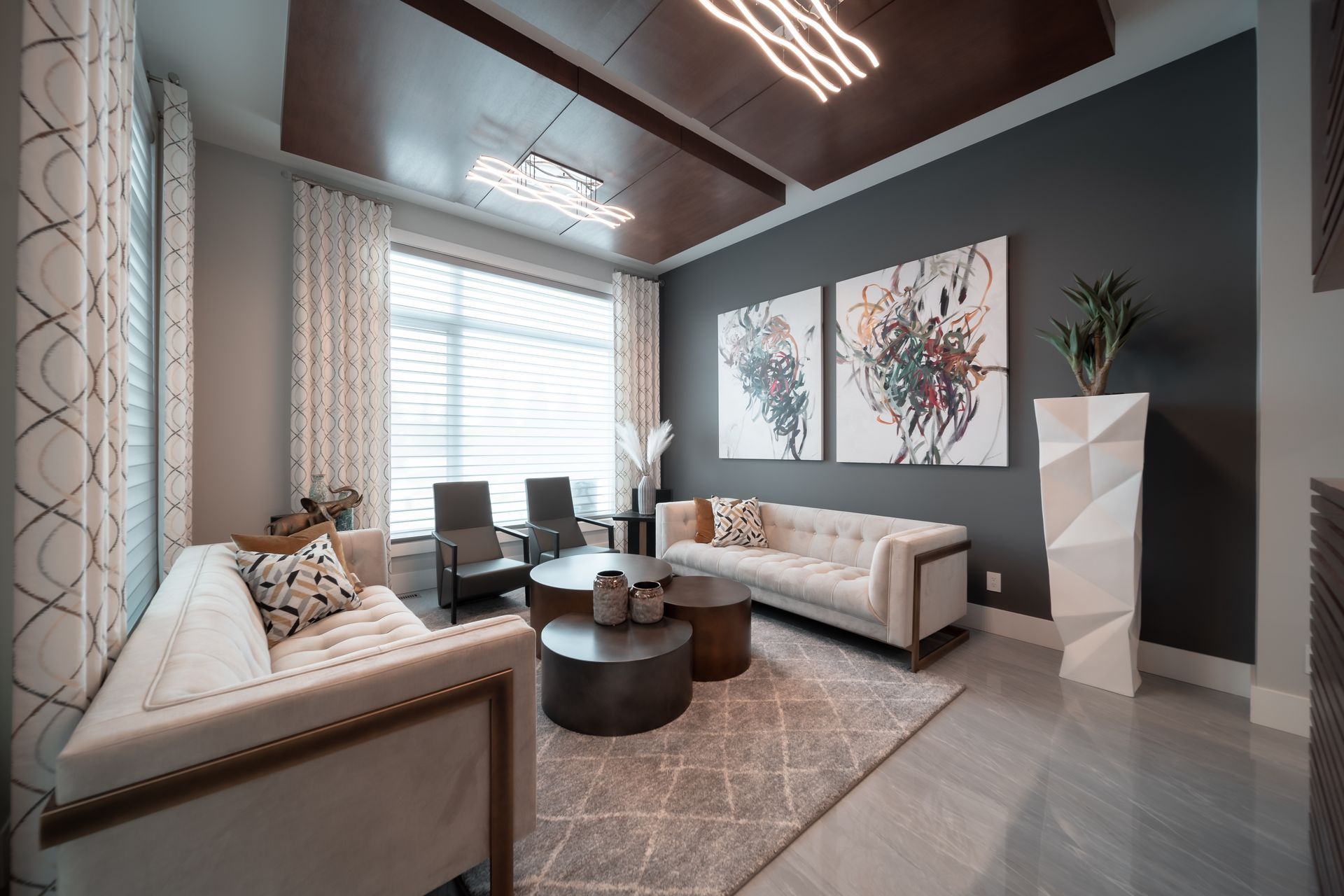 A living room with a couch , two chairs , a coffee table and two paintings on the wall.