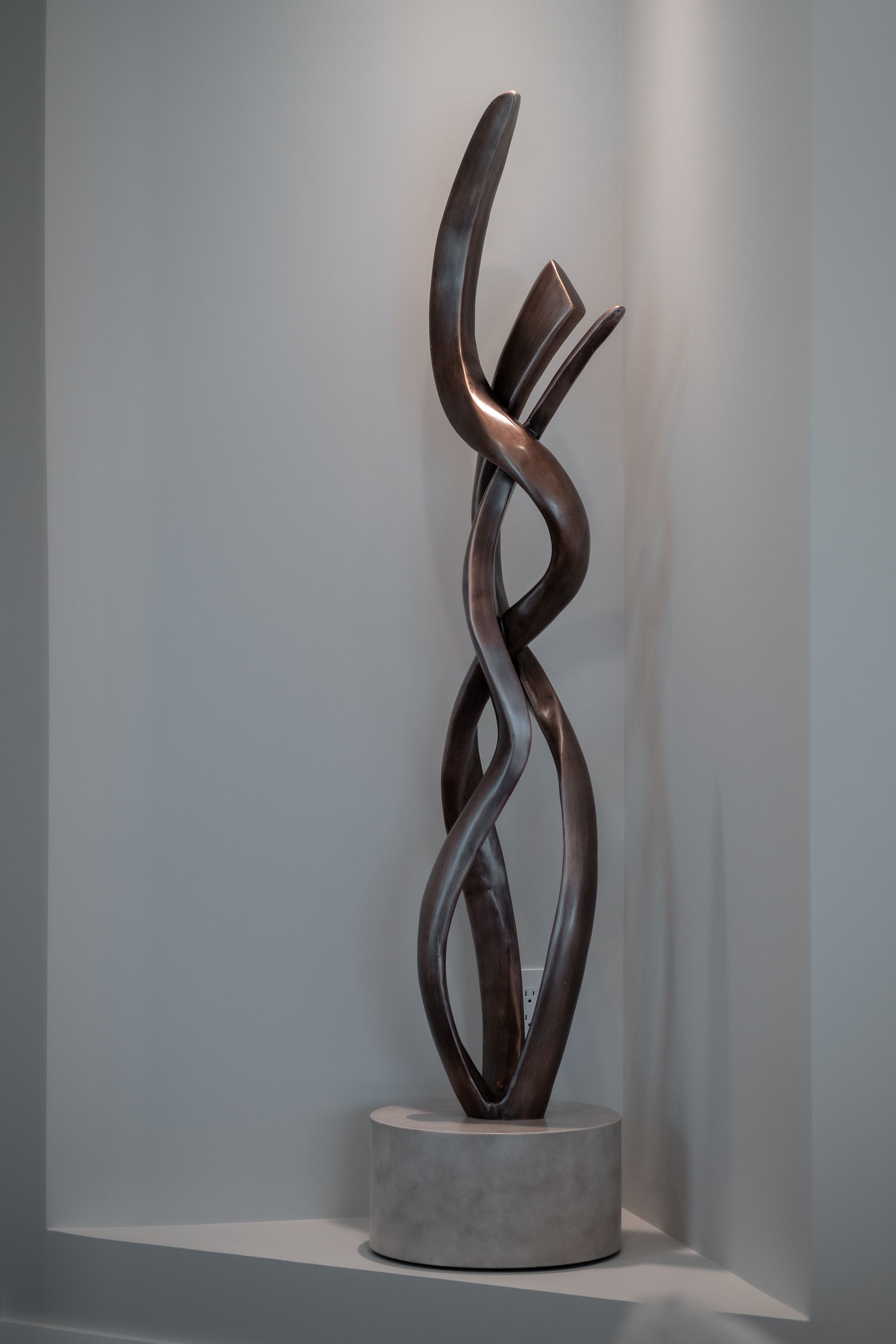 A sculpture is sitting on a shelf in a corner of a room.
