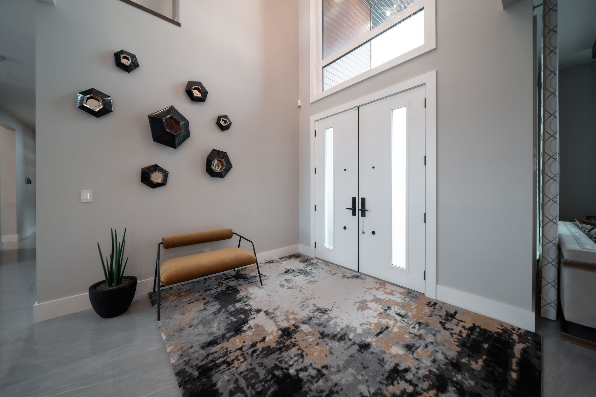 A living room with a bench and a rug in front of a door.