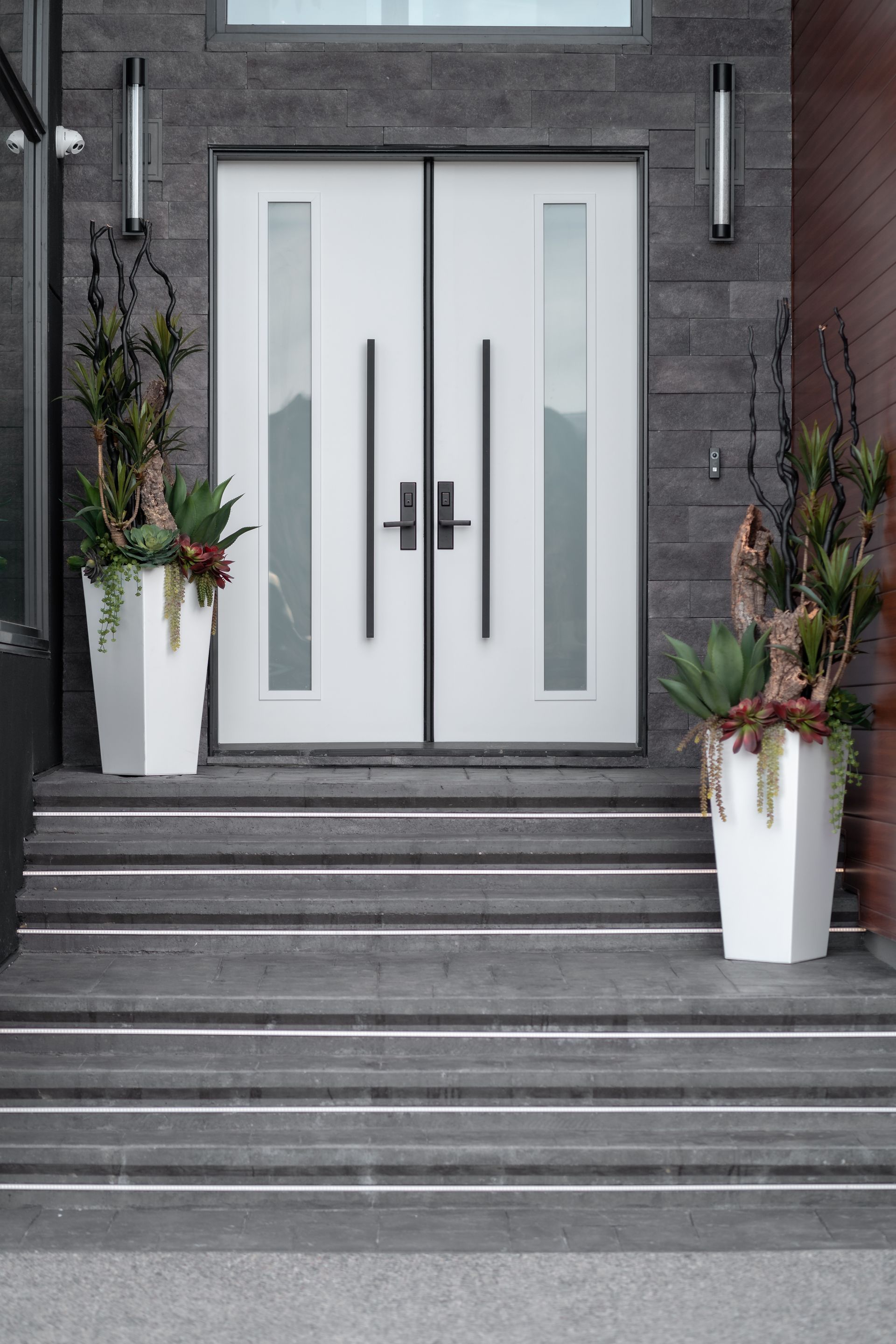 A white door with two potted plants in front of it