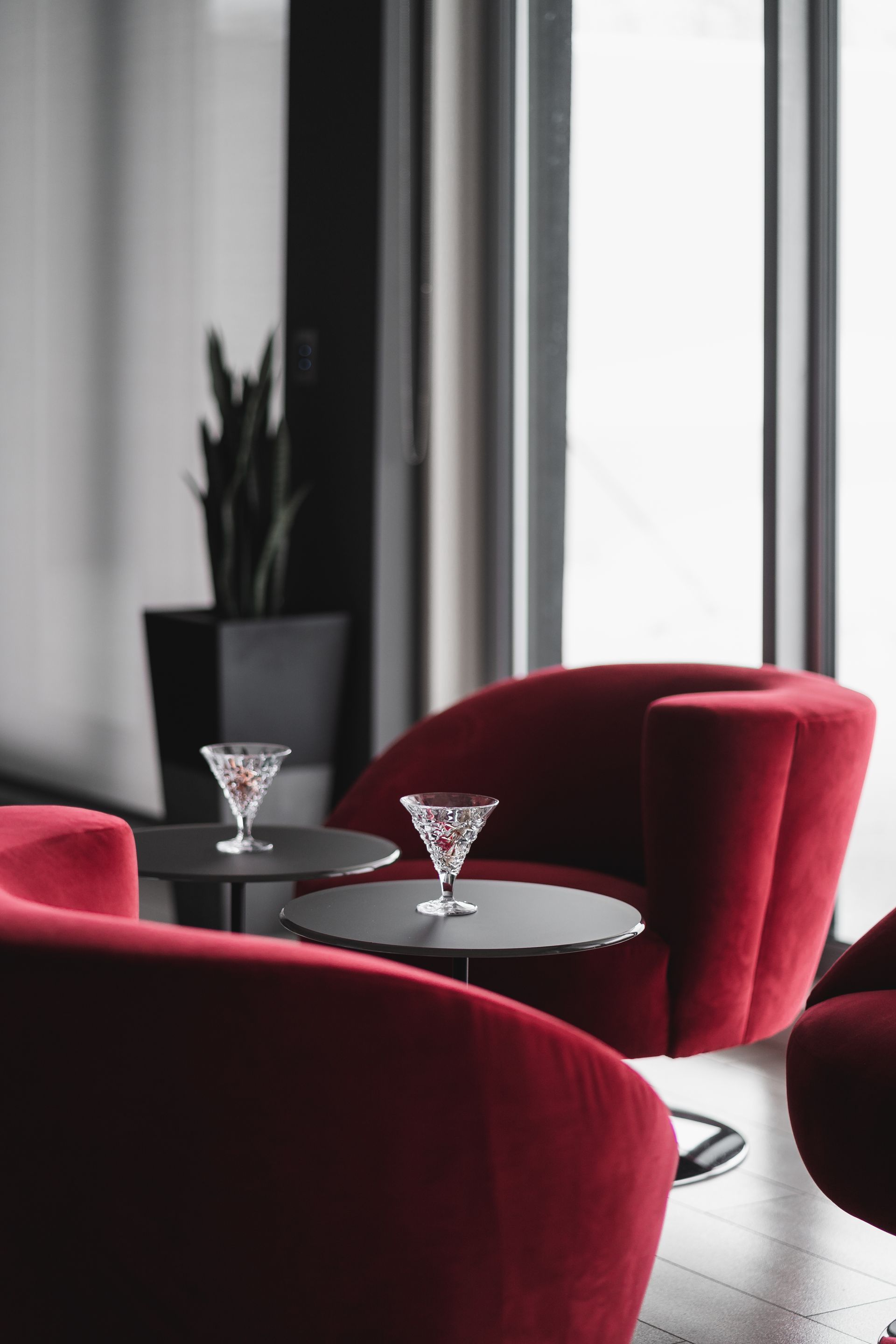 A room with red chairs and tables with martini glasses on them
