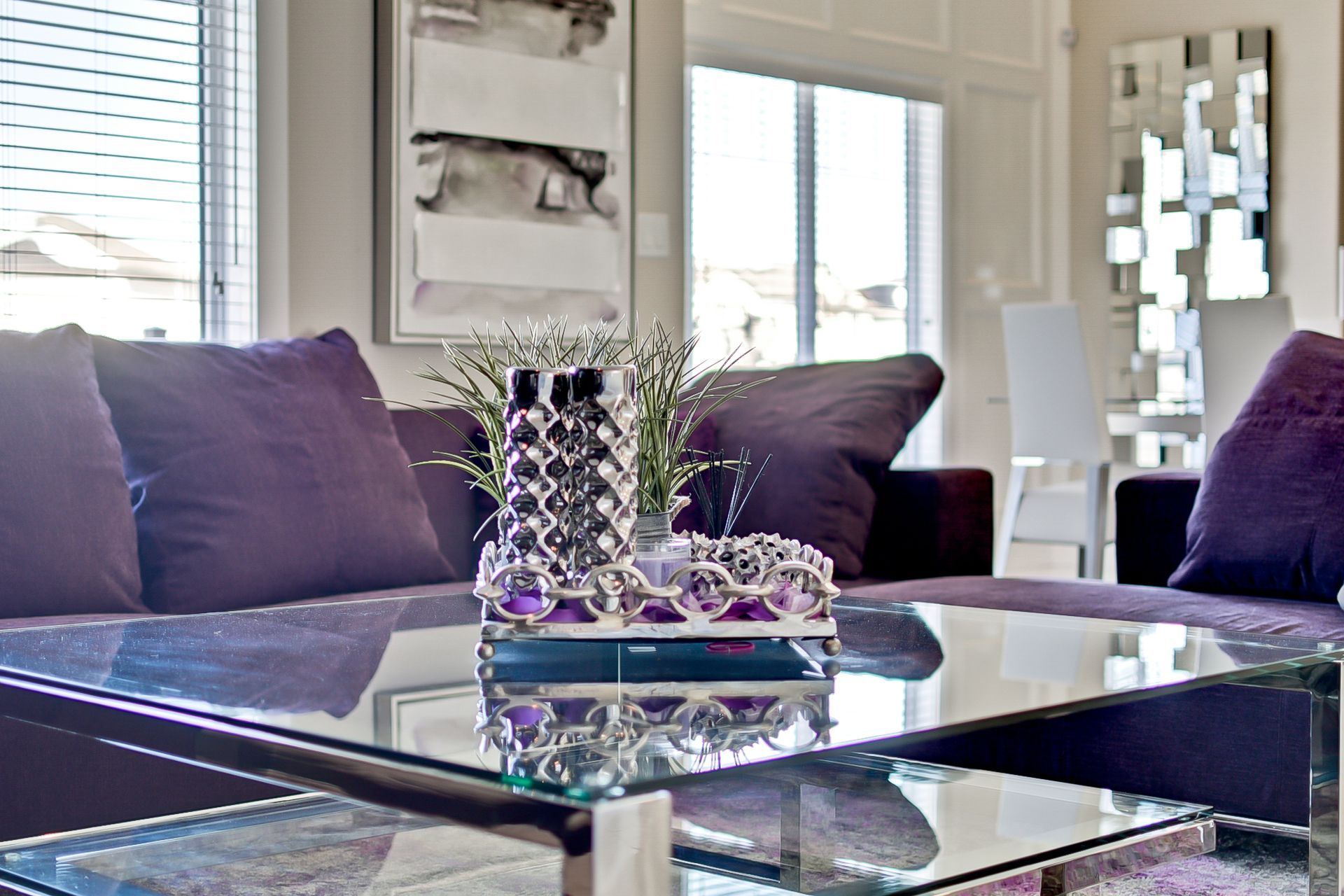 A living room with purple furniture and a glass coffee table