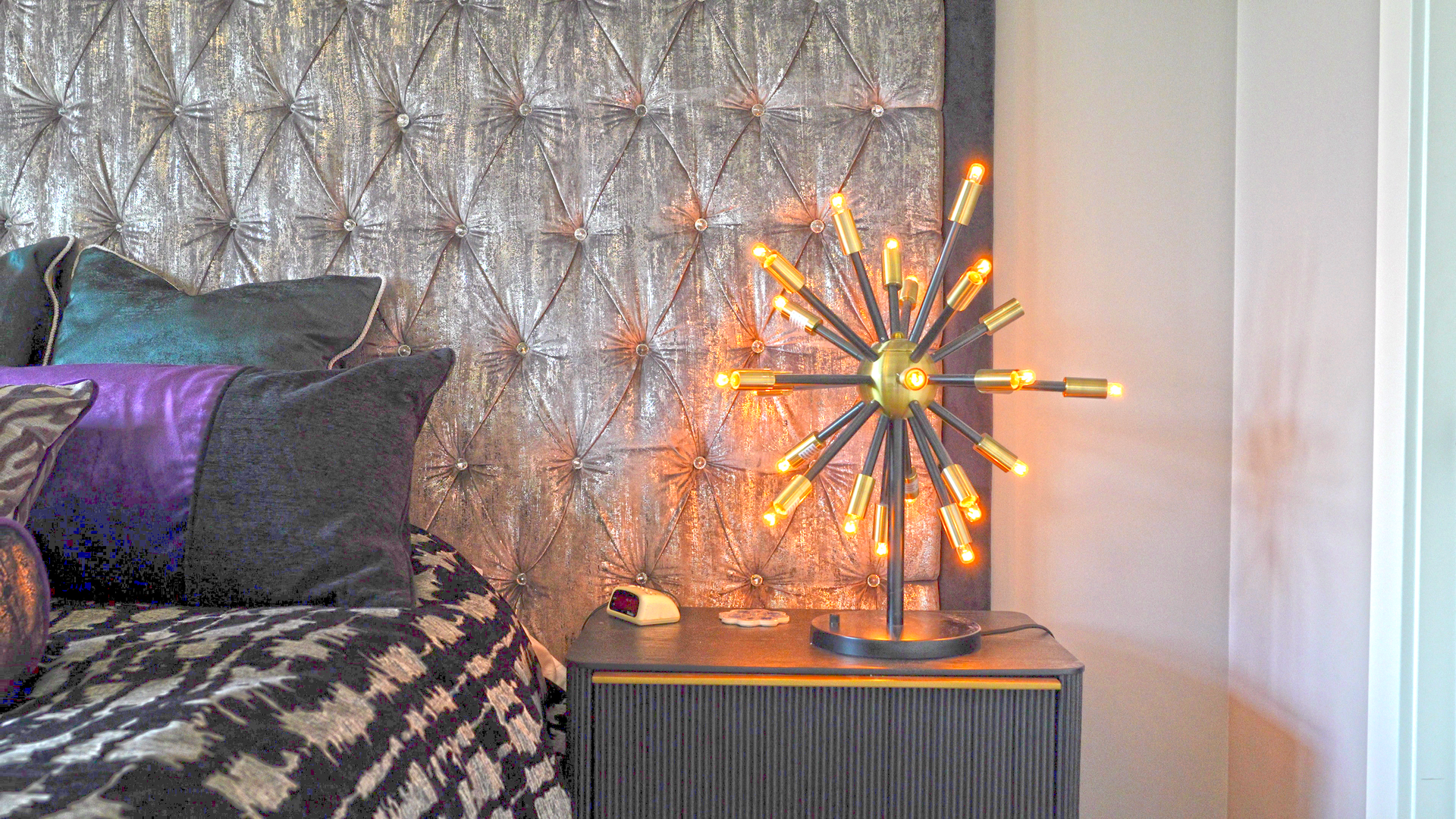 A bedroom with a bed , nightstand , and lamp.