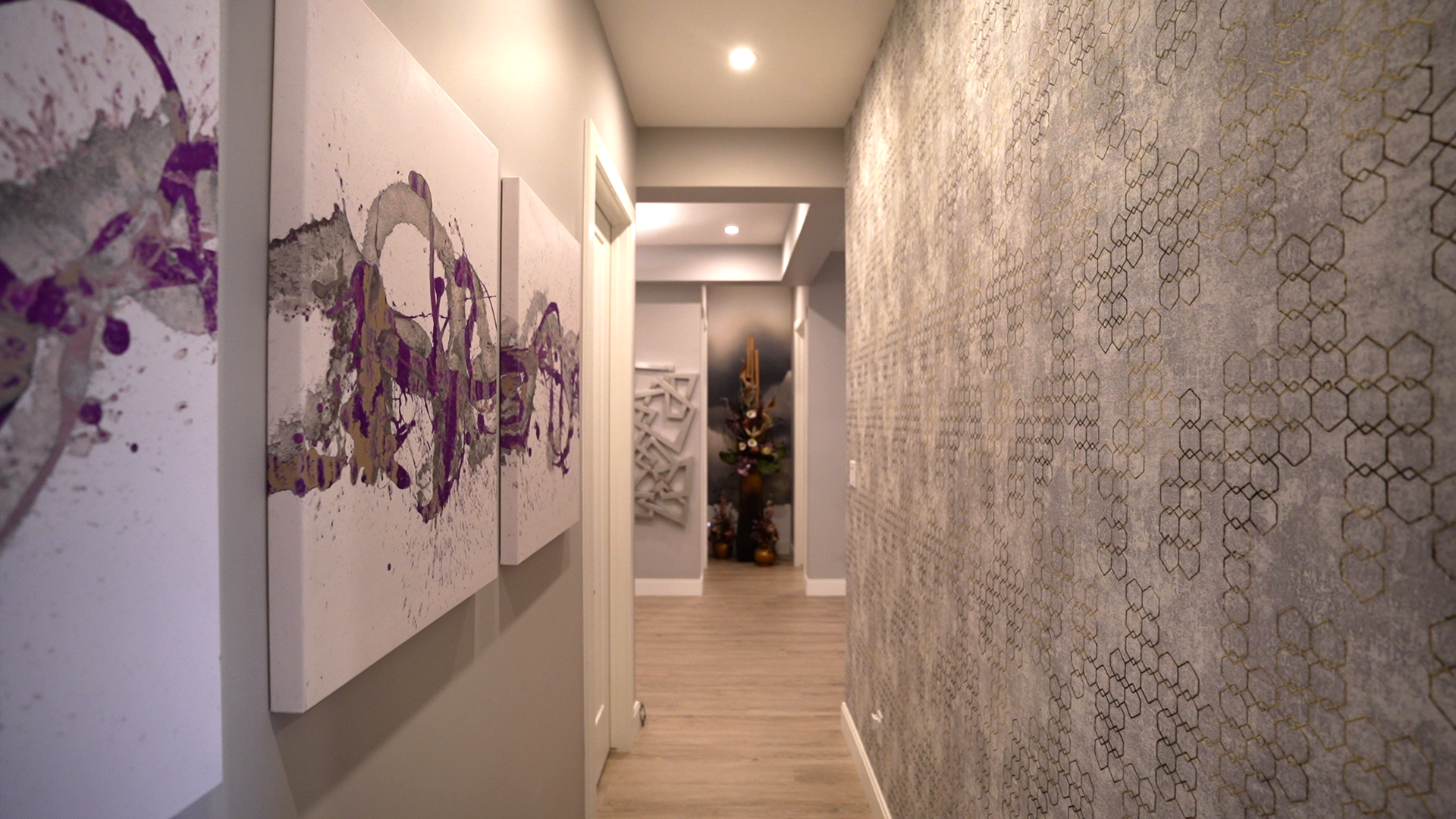 A long hallway with purple paintings on the wall.