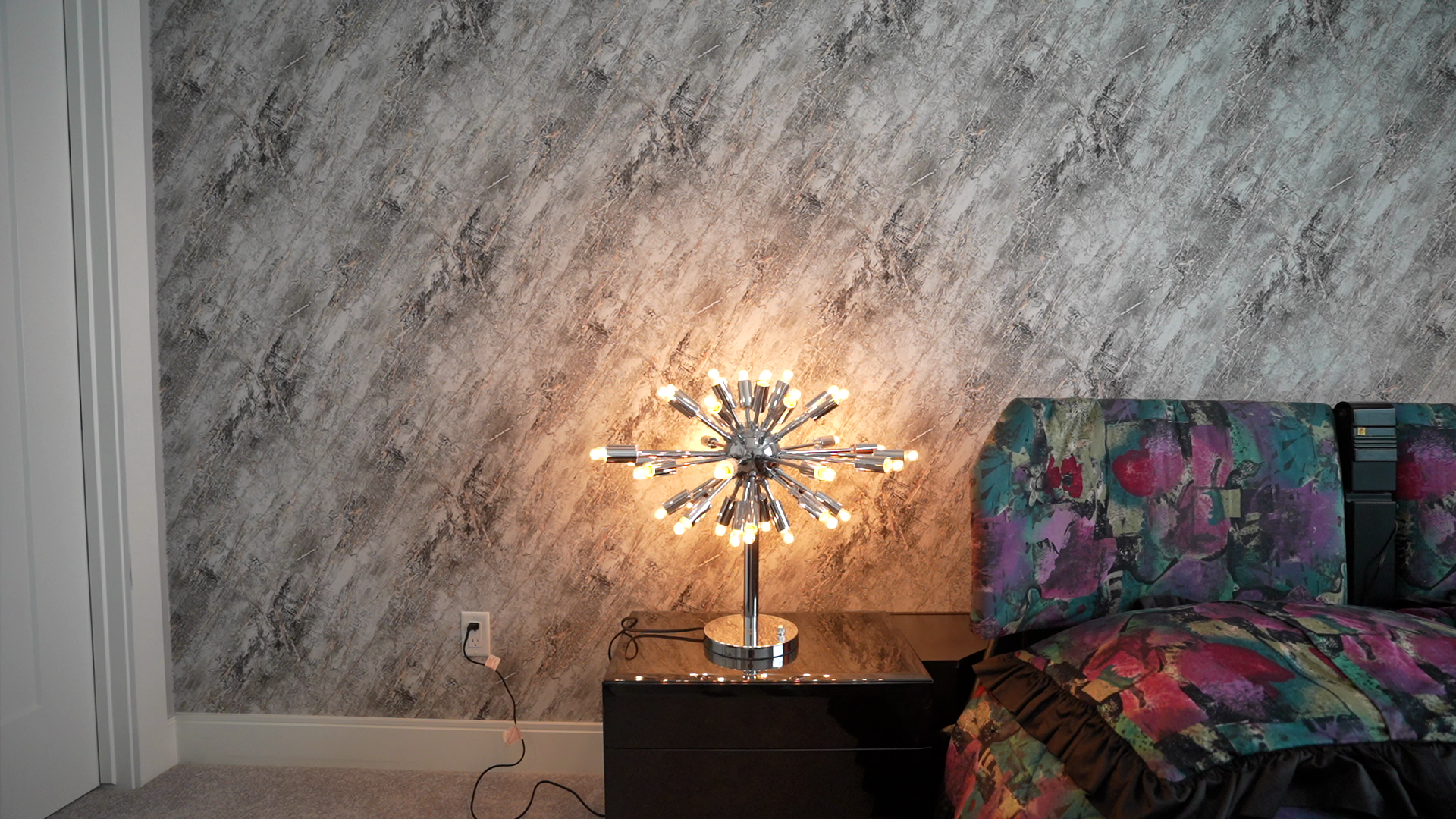 A lamp is sitting on a nightstand in a bedroom next to a bed.