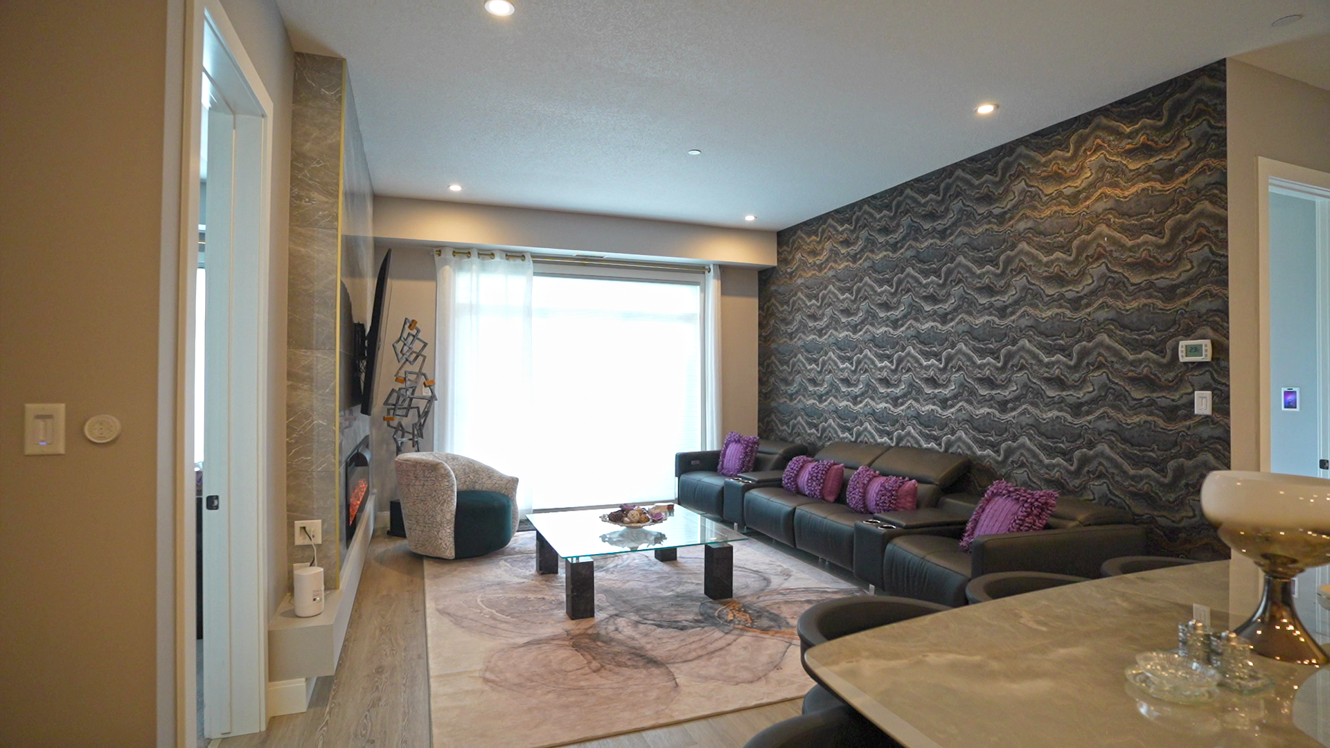 A living room with a couch , table , chairs and a large window.