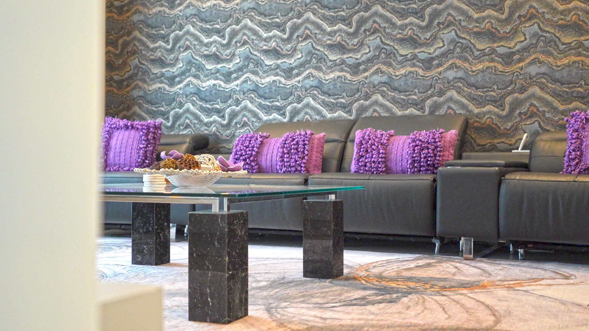 A living room with a couch , coffee table , and purple pillows.