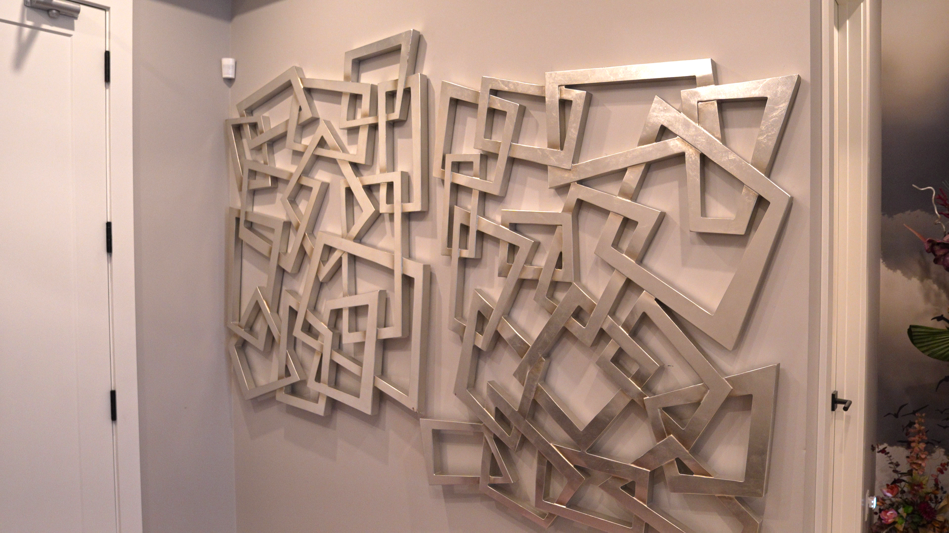 A large sculpture is hanging on a wall in a hallway.