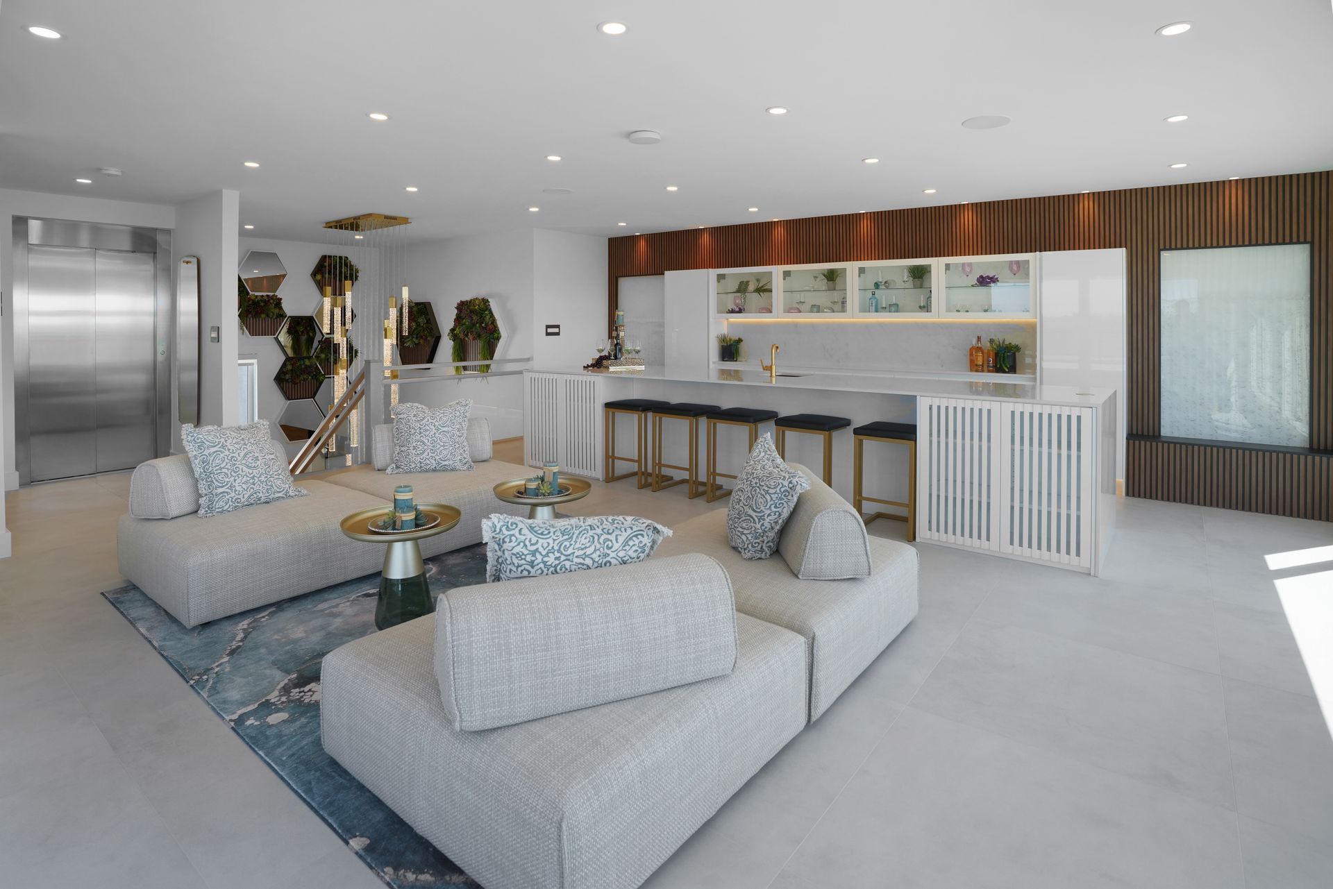 A living room with a lot of furniture and a kitchen in the background.
