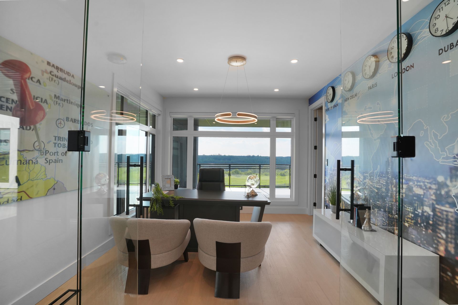 A room with a desk , chairs , and clocks on the wall.