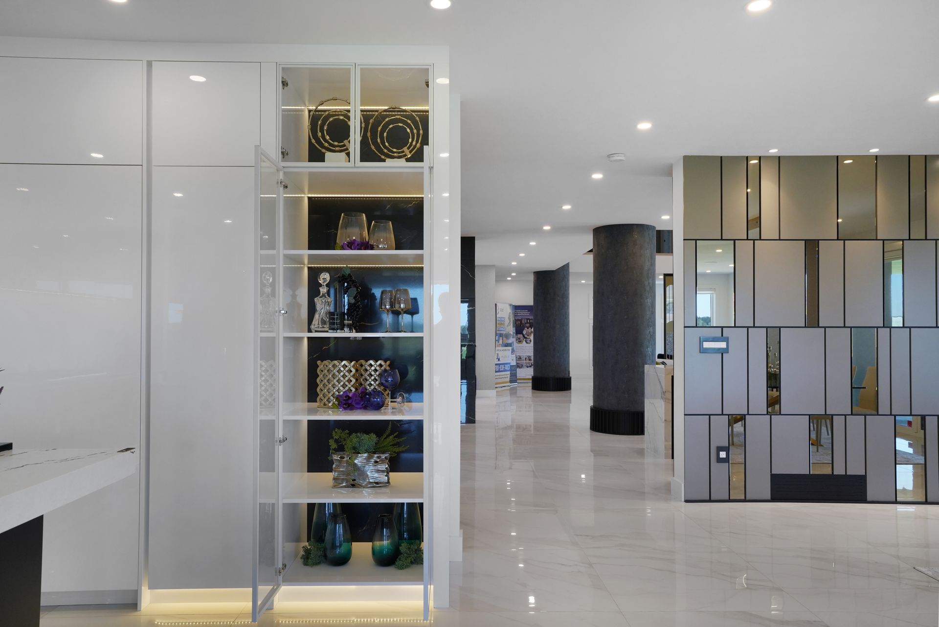 There is a shelf in the middle of the room with vases on it.
