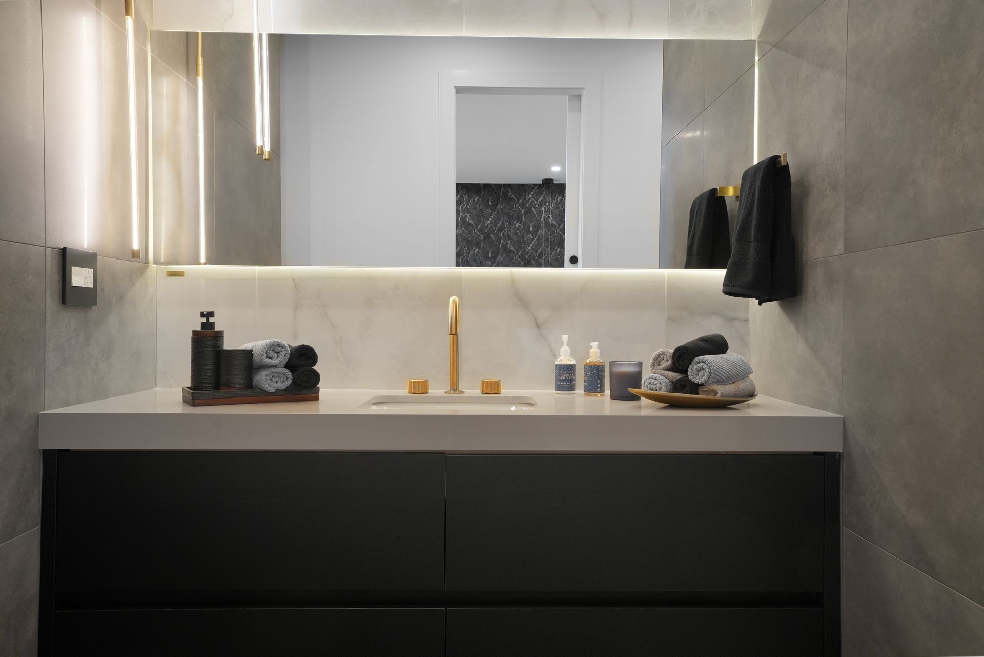 A bathroom with a sink , mirror and towels on the counter.