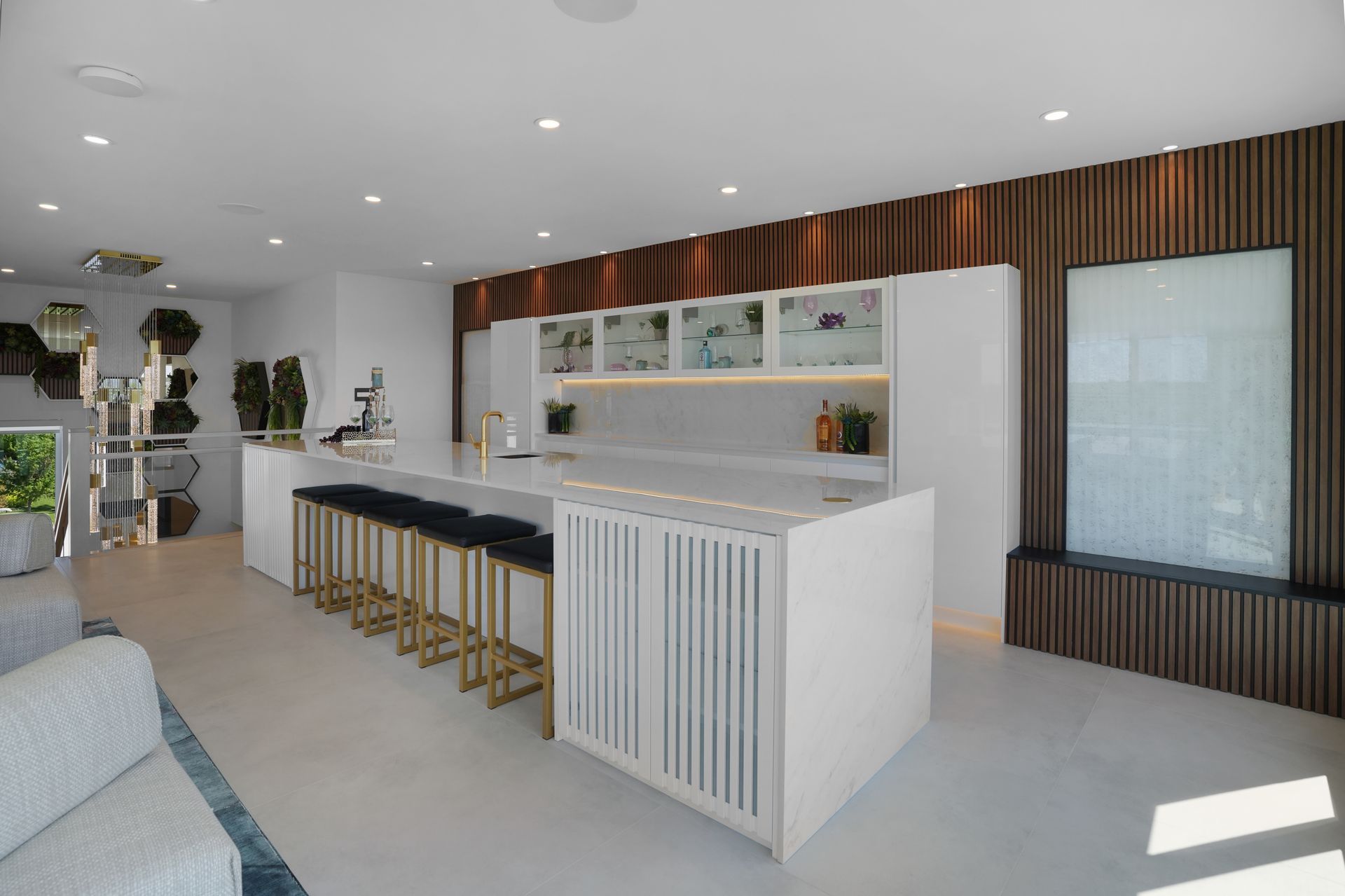 A kitchen with a large island and stools in a living room.