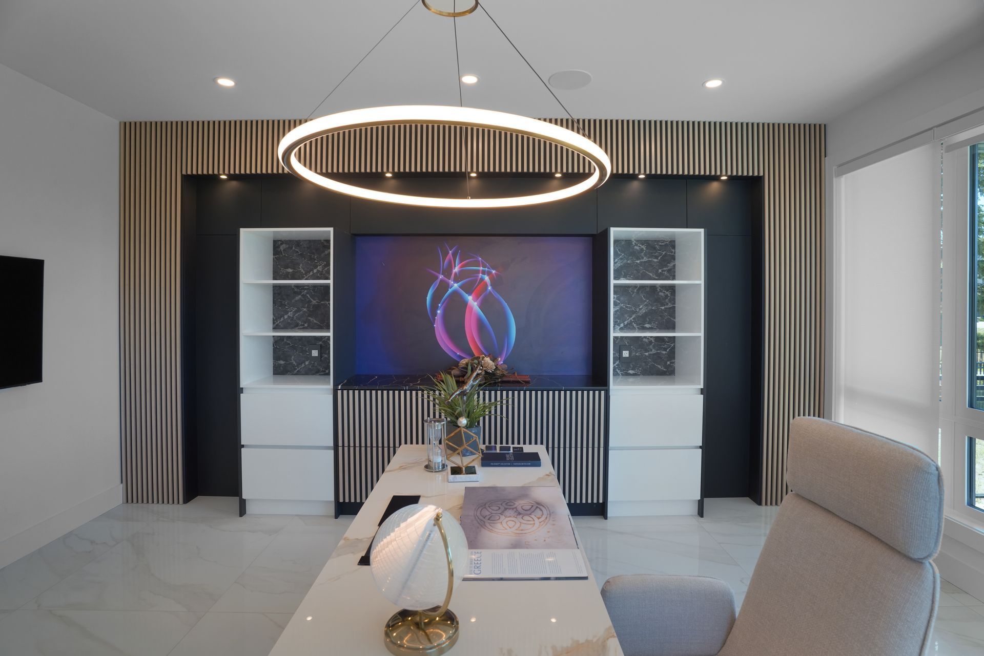 A living room with a desk , chair , television and a large screen.