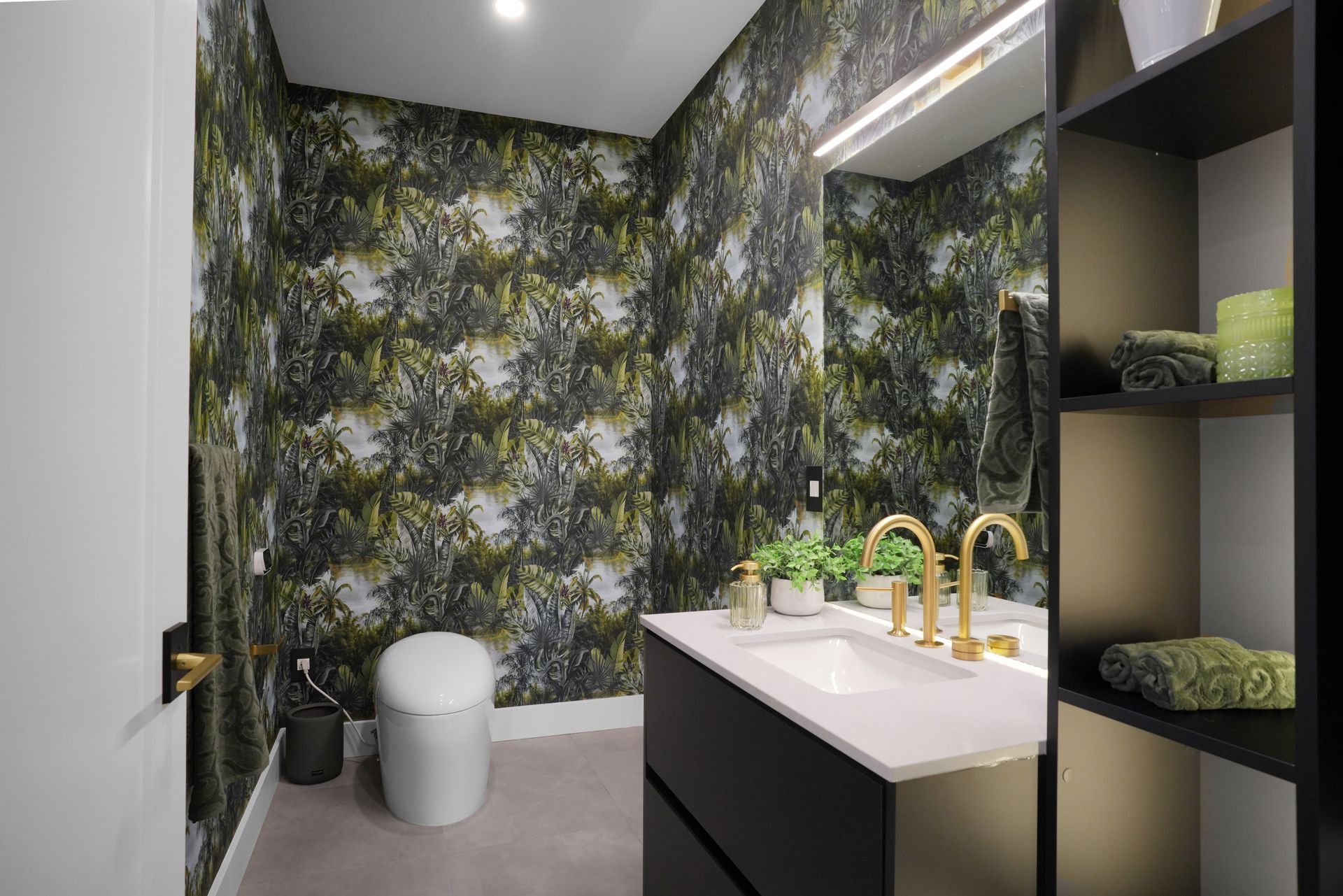 A bathroom with a toilet , sink , mirror and shelves.