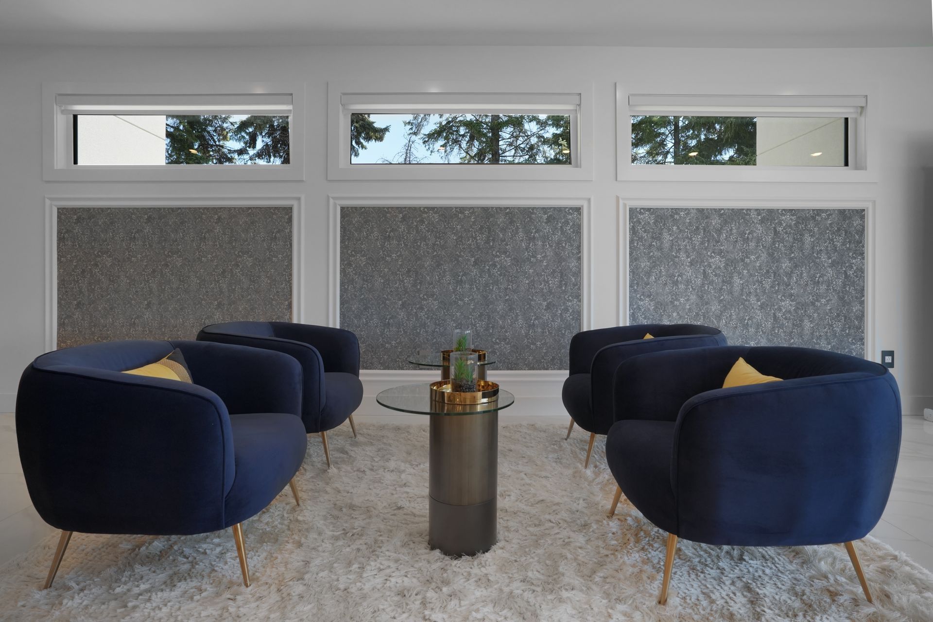 A living room with blue chairs and a glass coffee table.