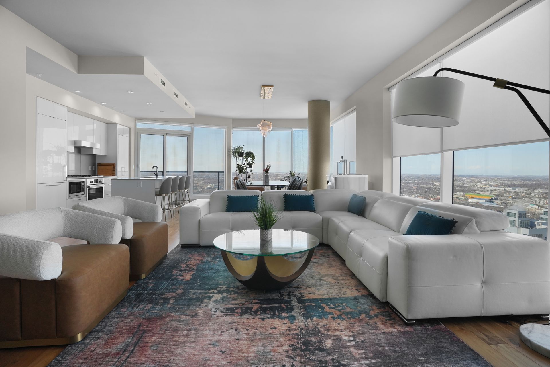 Luxurious modern living room with white sectional sofa, large windows, and colorful rug.