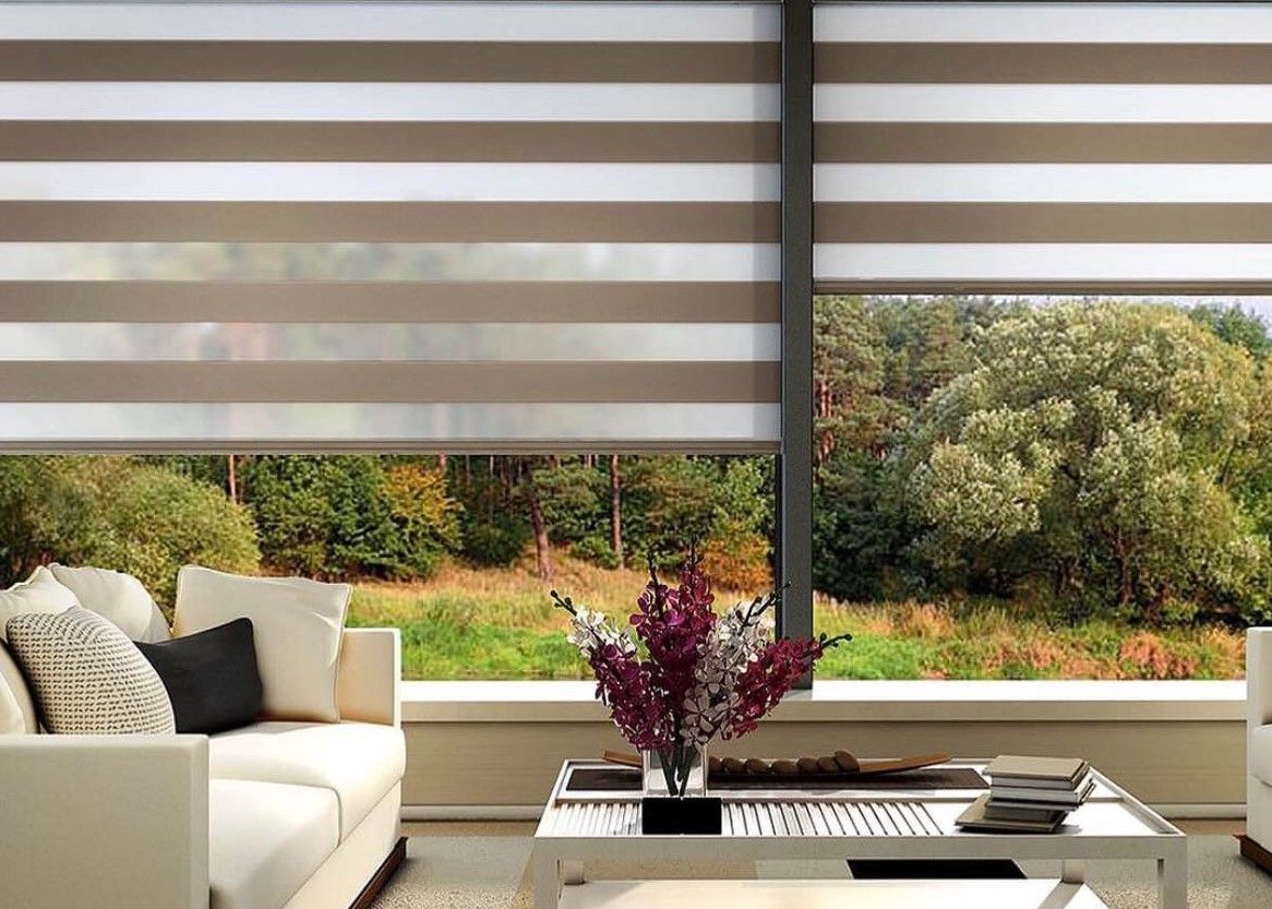 Living room with horizontal striped blinds, beige sofa, and a view of trees.