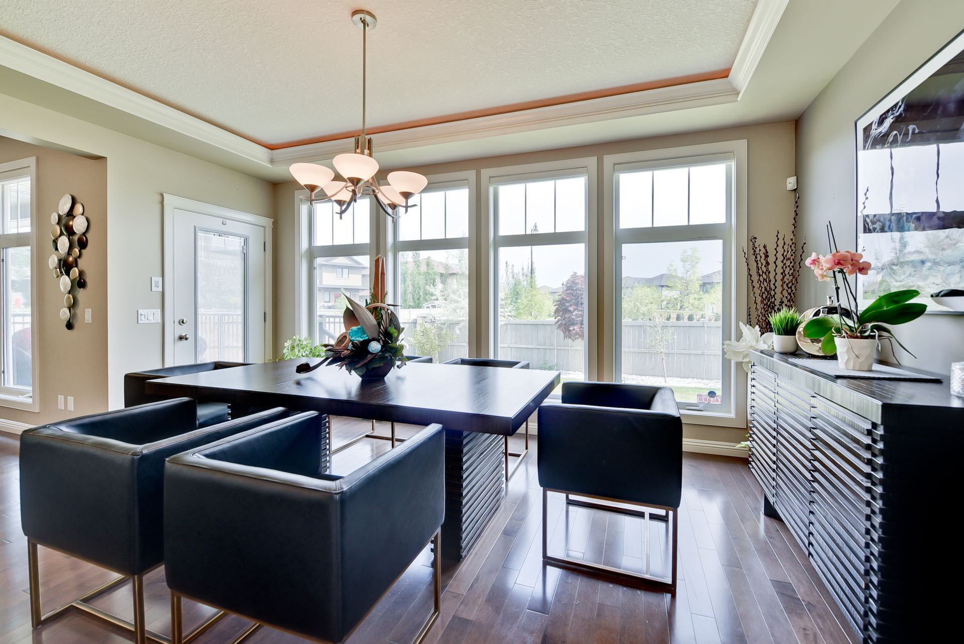 A dining room with a table and chairs and lots of windows