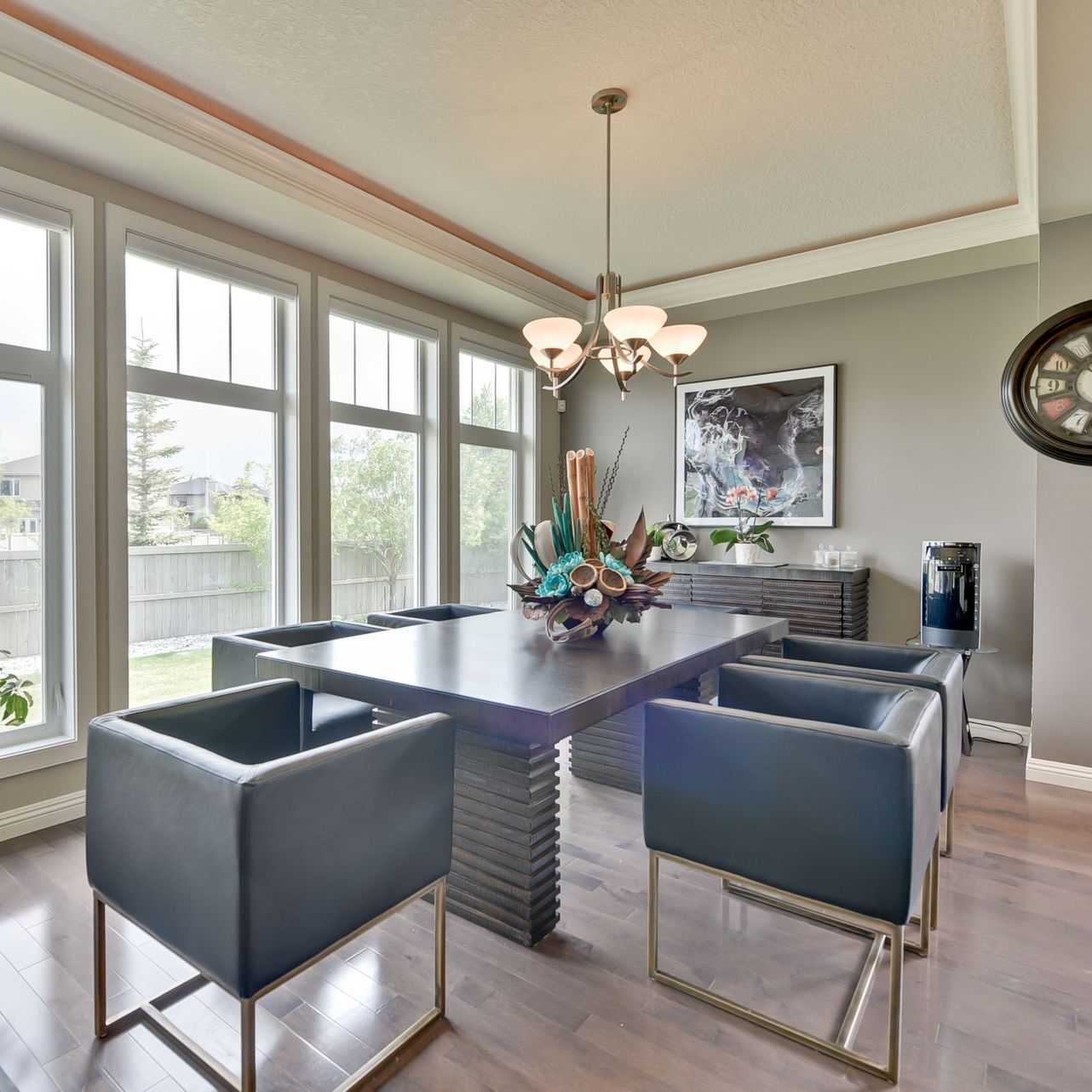 A dining room with a table and chairs and a clock on the wall