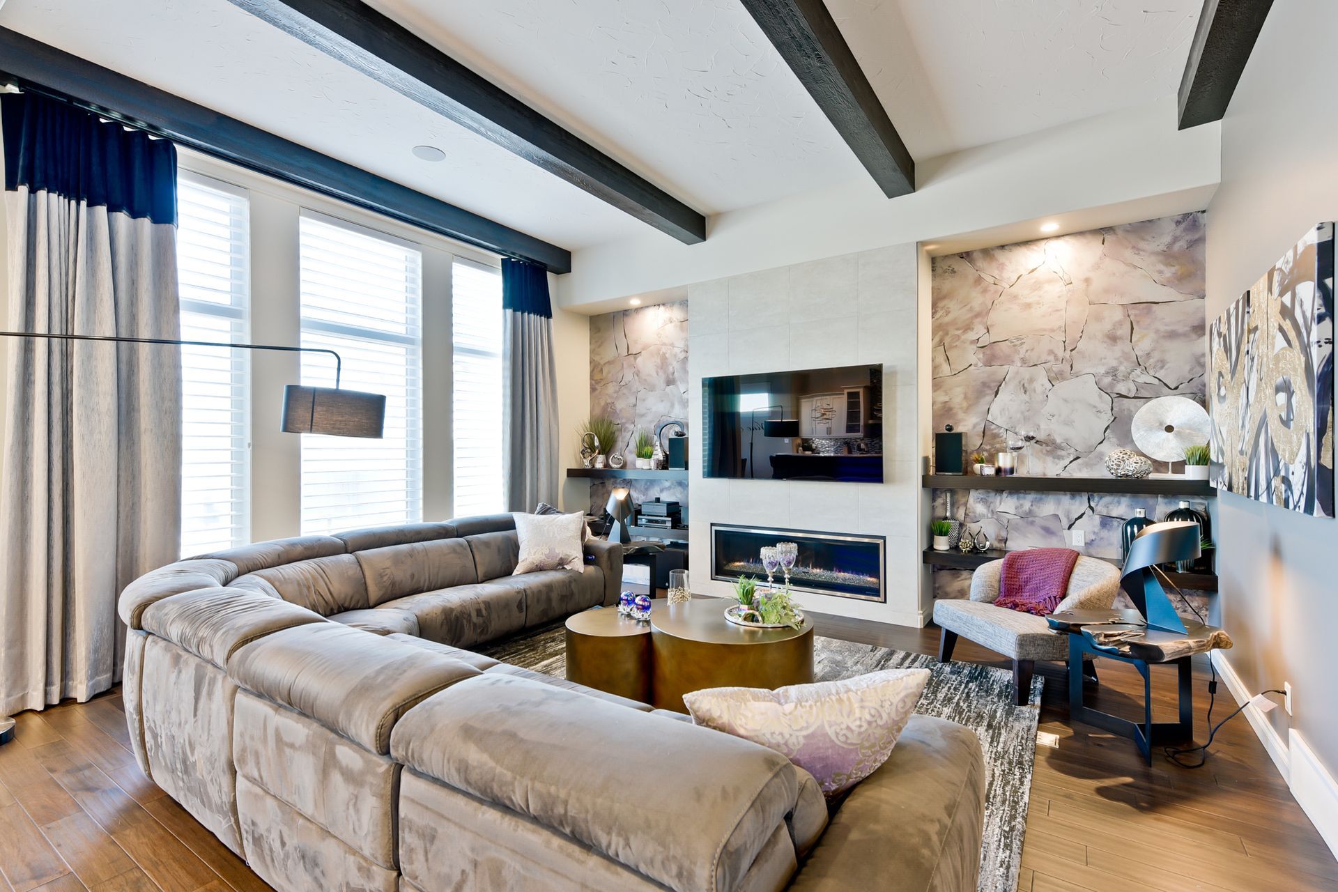 A living room with a large sectional couch and a flat screen tv on the wall.