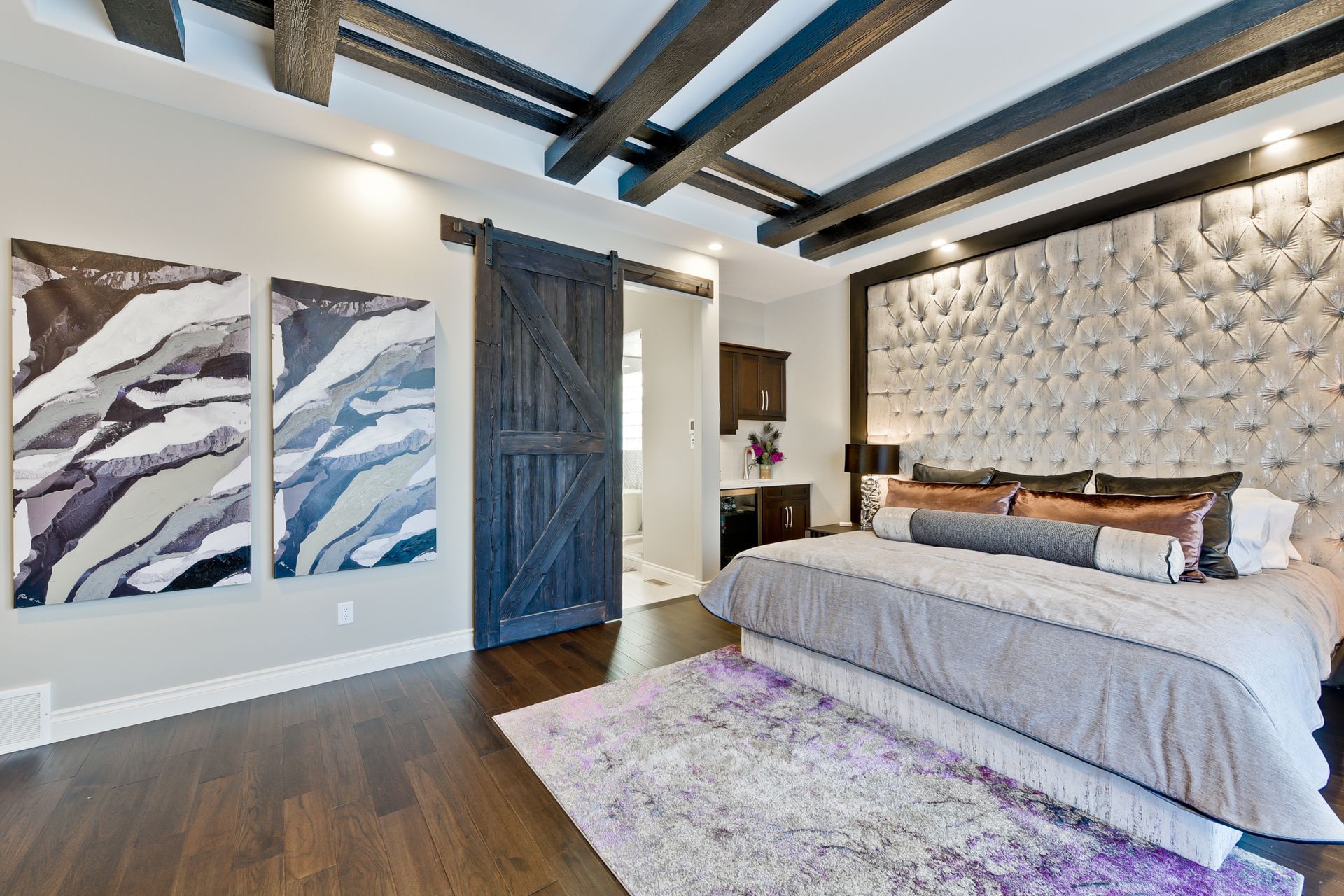 A bedroom with a large bed and a sliding barn door.