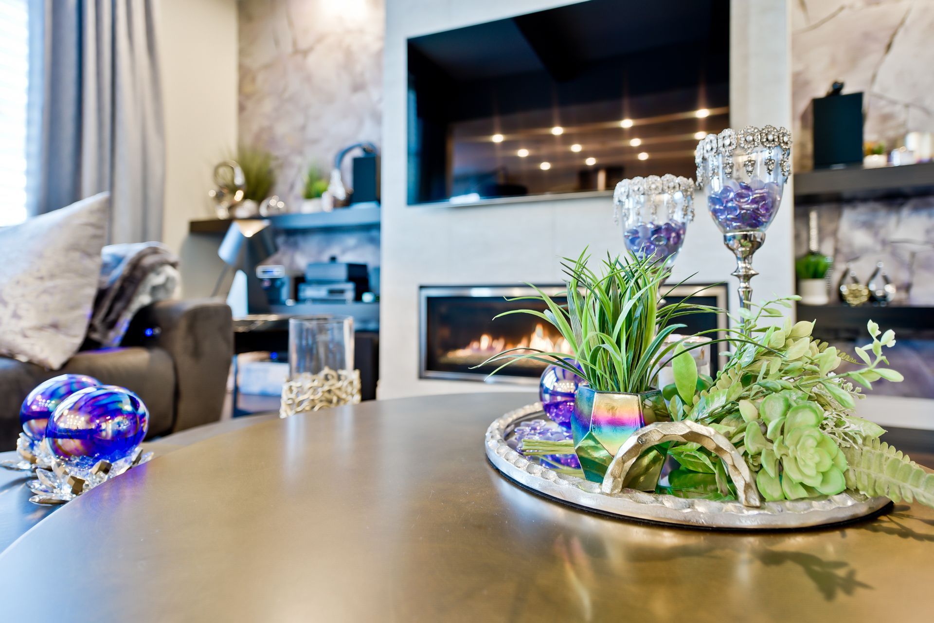 A living room with a fireplace and a coffee table with a tray of flowers on it.