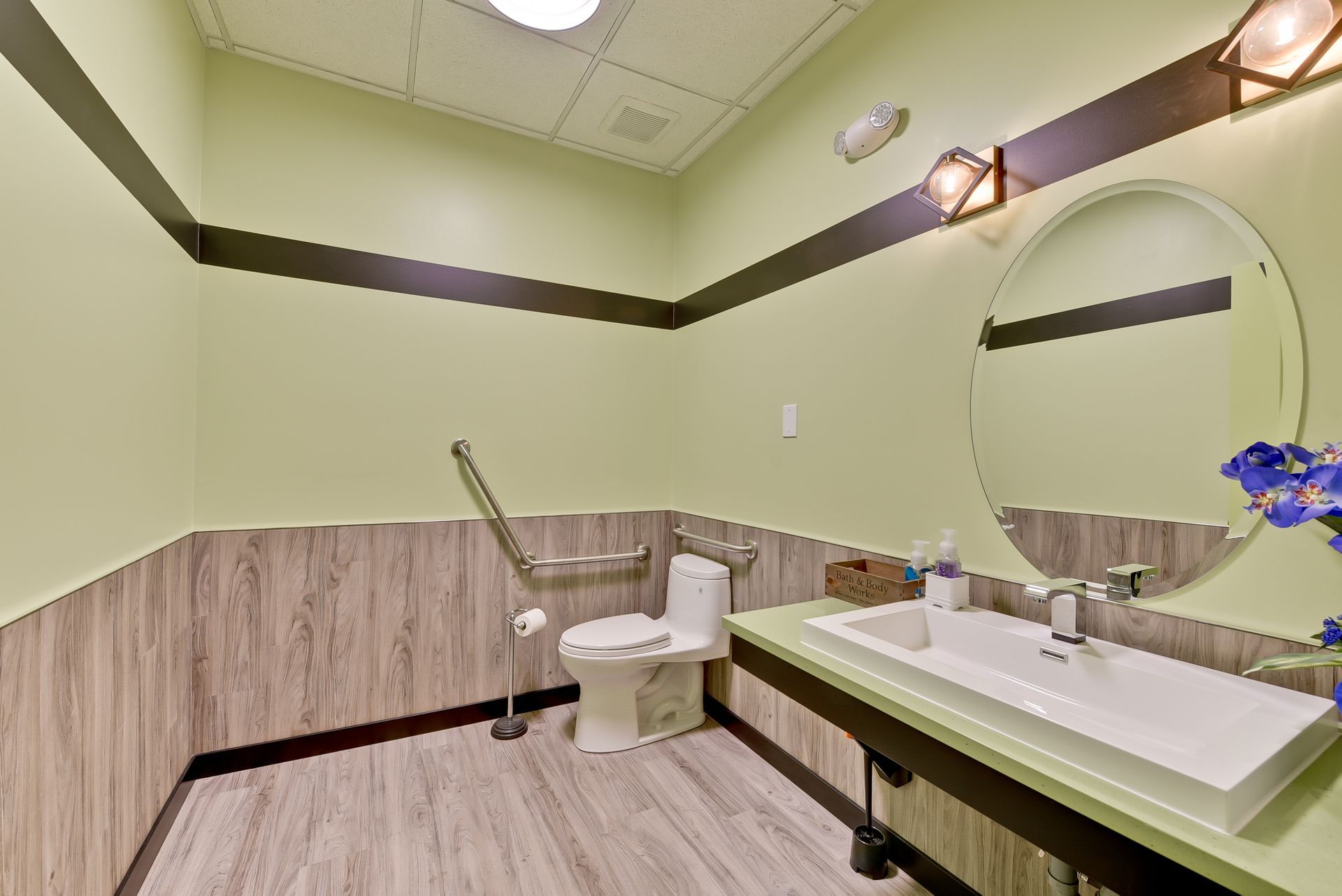 A bathroom with a toilet , sink and mirror.